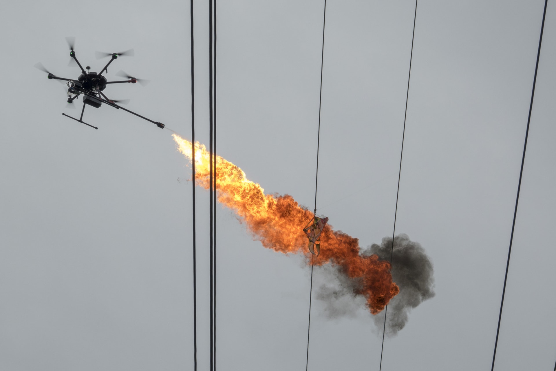 <p>A drone operated by staff of Hainan Power Grid Corporation emits flame to burn down trash from power lines, in Haikou, Hainan province, China on November 16, 2017</p>
