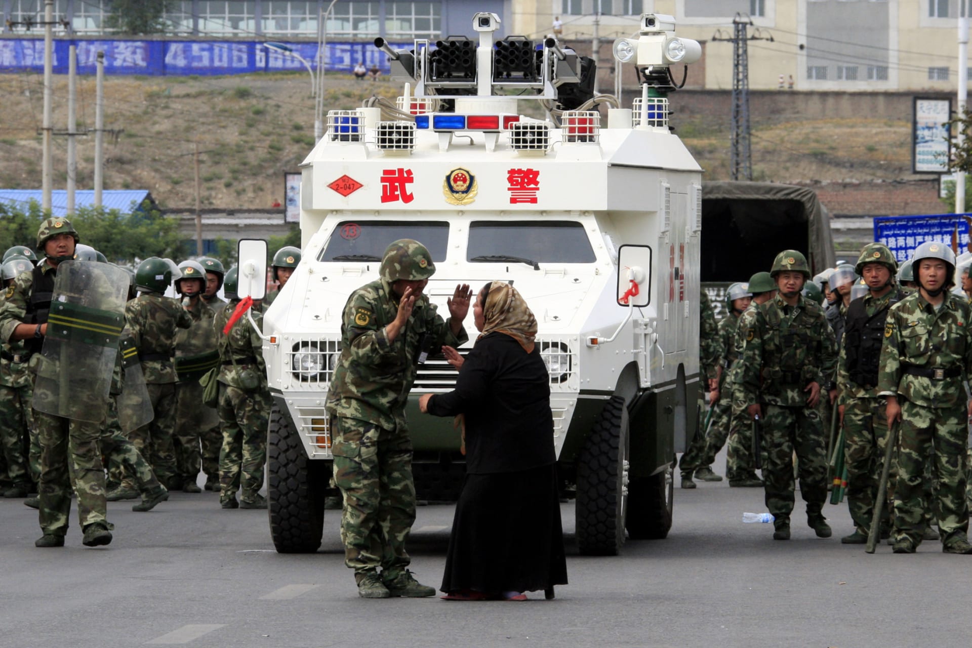 <p>A woman on a crutch argues with a Chinese paramilitary police in front of an armoured personnel carrier in the city of Urumqi in China’s Xinjiang Autonomous Region in 2009.</p>
