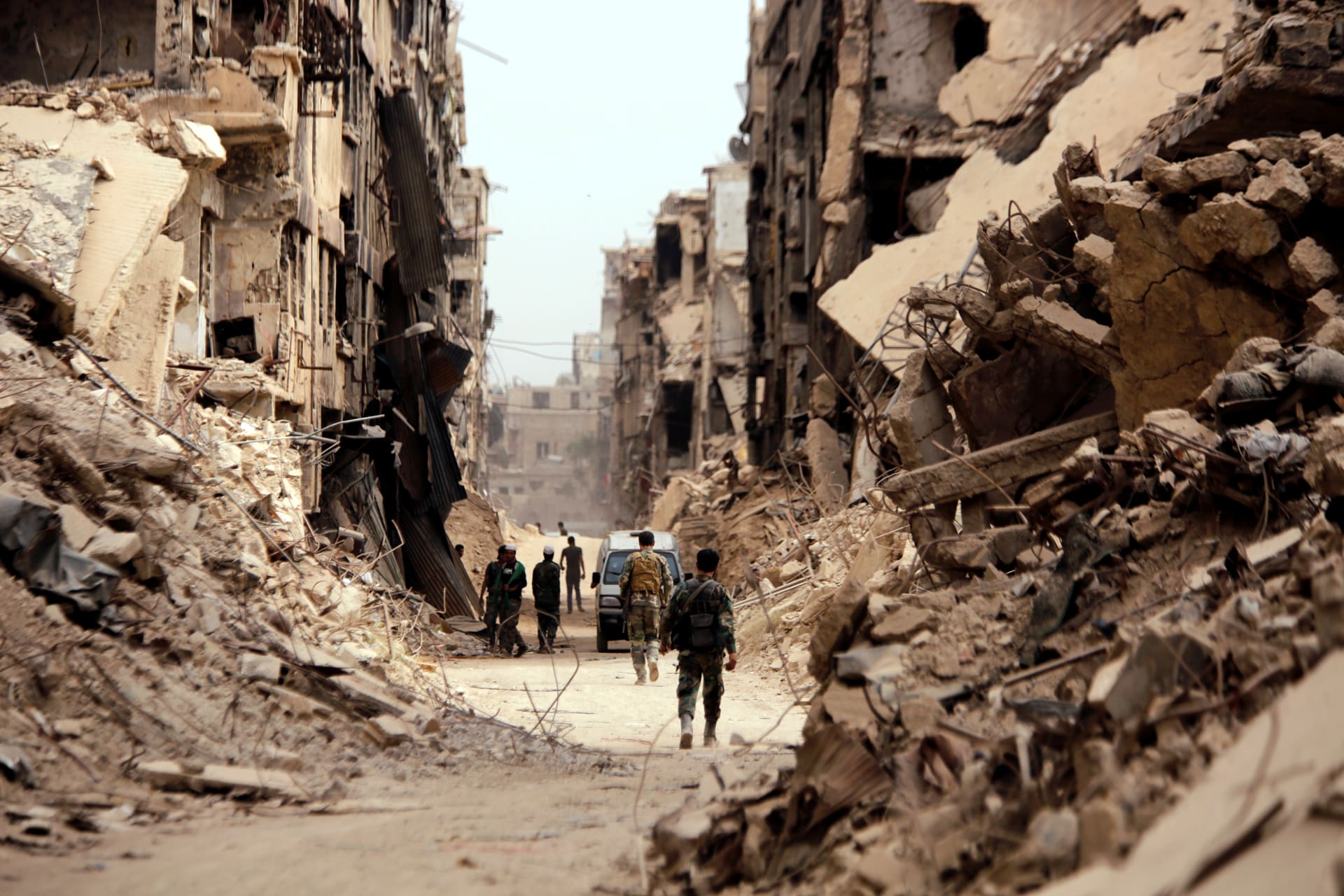 <p>Soldiers walk past damaged buildings in Damascus, Syria, on May 22, 2018.</p>
