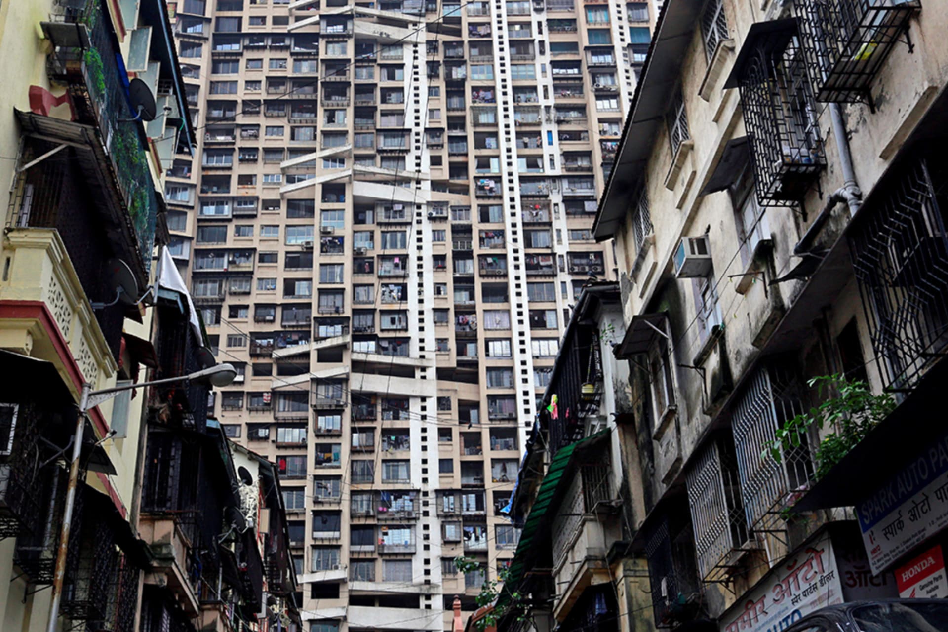 <p>A residential tower rises behind older residential buildings in Mumbai, India, in 2017.</p>
