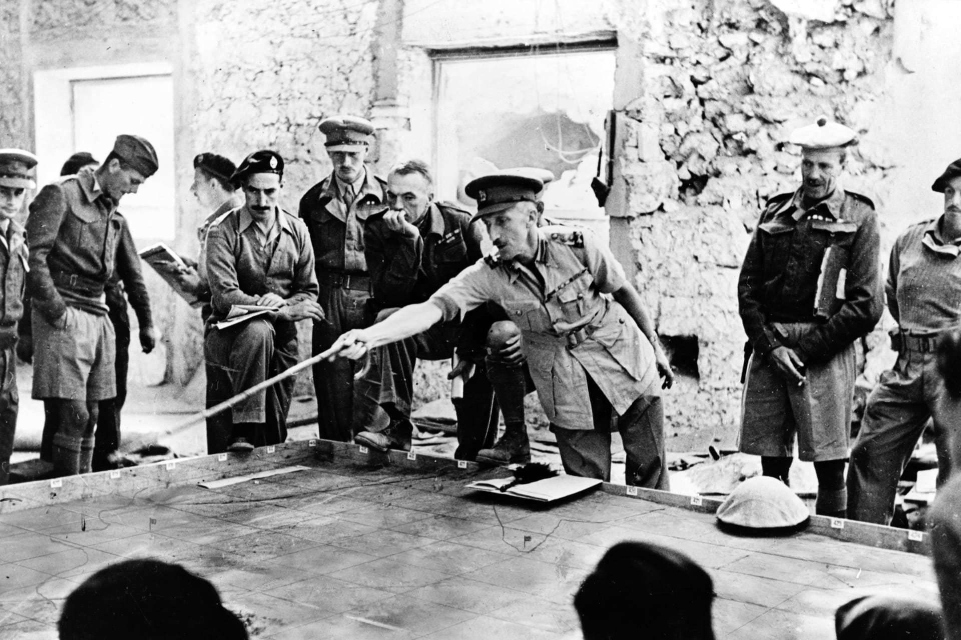 <p>The second battle of Libya during World War II. A British brigadier commanding tank units in Tobruk instructs officers on an operation, using a sand table for demonstration purposes.</p>
