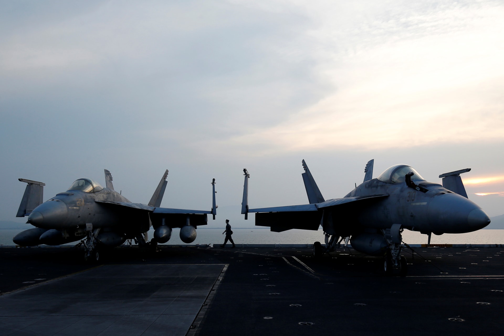 <p>A sailor walks behind aircraft on the U.S. Navy carrier USS Carl Vinson after it docked at a port in Danang, Vietnam, on March 5, 2018</p>
