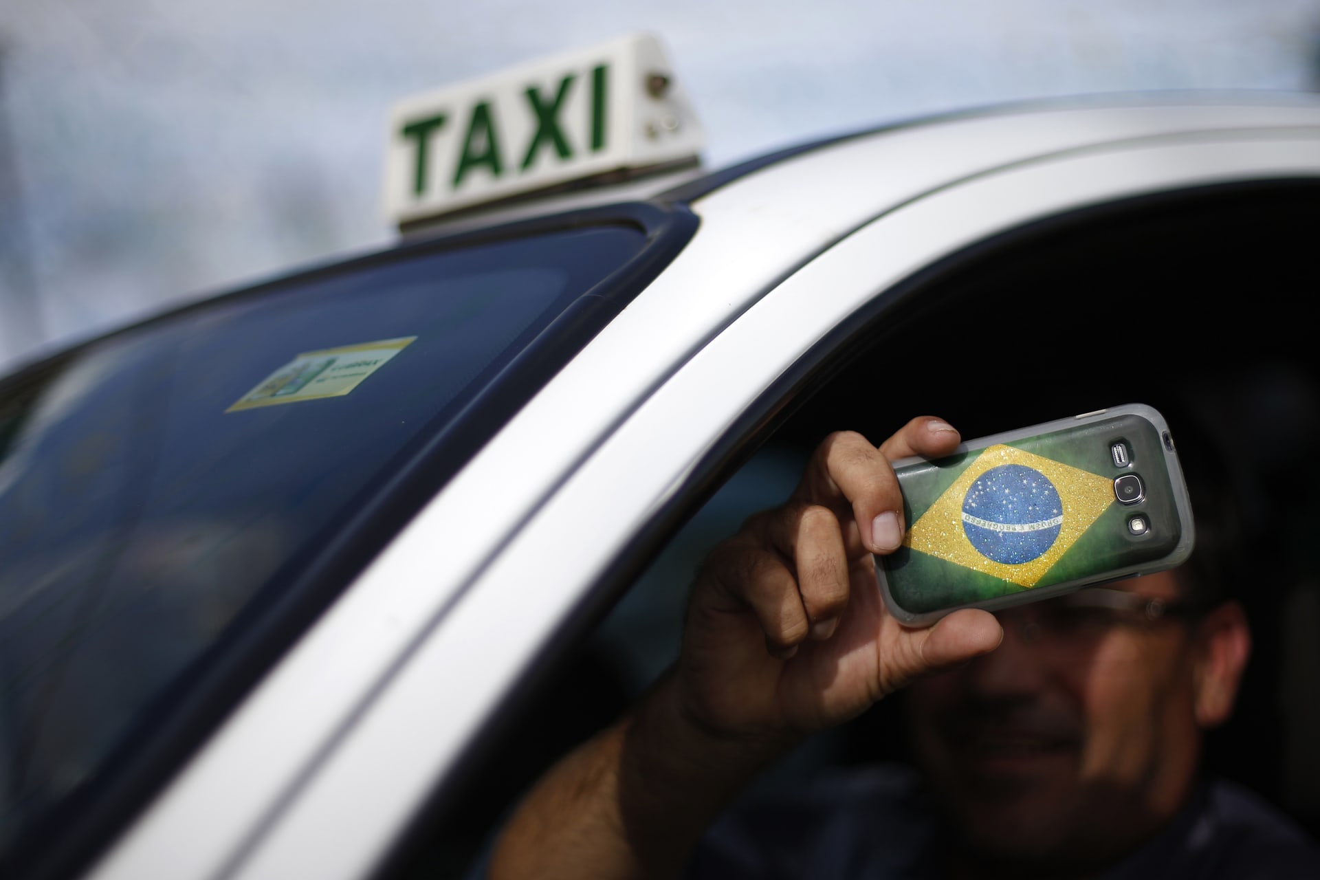 <p>A taxi driver takes photos at the slum of Varjao on the outskirts of Brasilia in 2014.</p>
