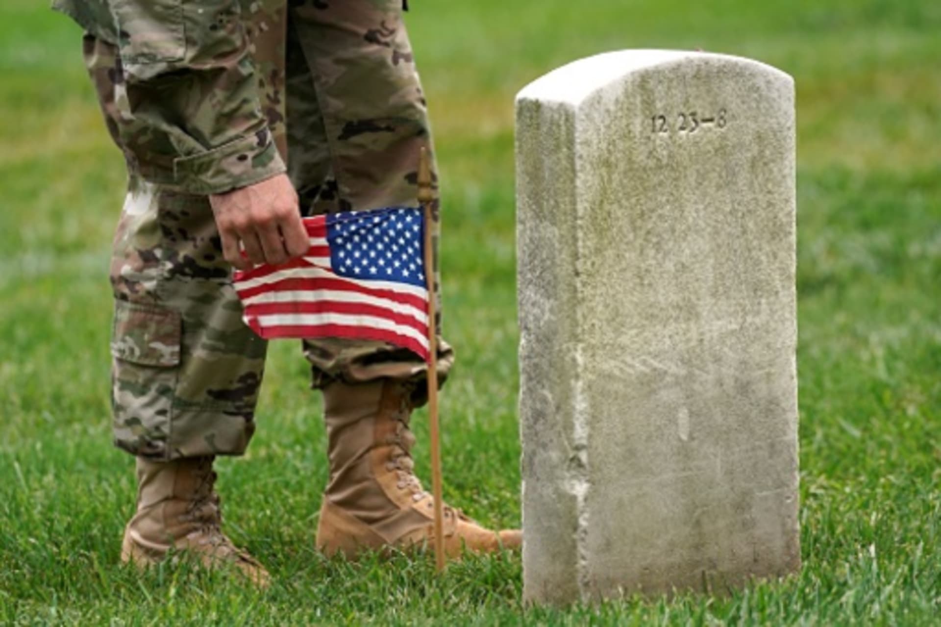 <p>A soldier from the 3rd U.S. Infantry Regiment places a flag at a headstone at Arlington National Cemetery. </p>
