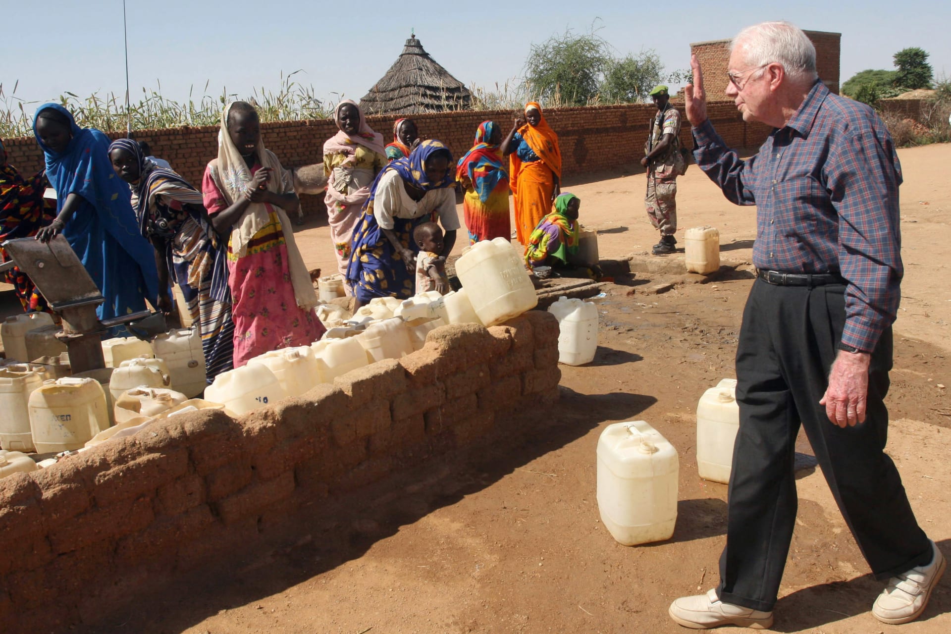 <p>Former U.S. President Jimmy Carter waves to internally displaced women at a water point in Kebkabiya town in North Darfur October 3, 2007. Carter began his fight against Guinea worm in 1986.</p>
