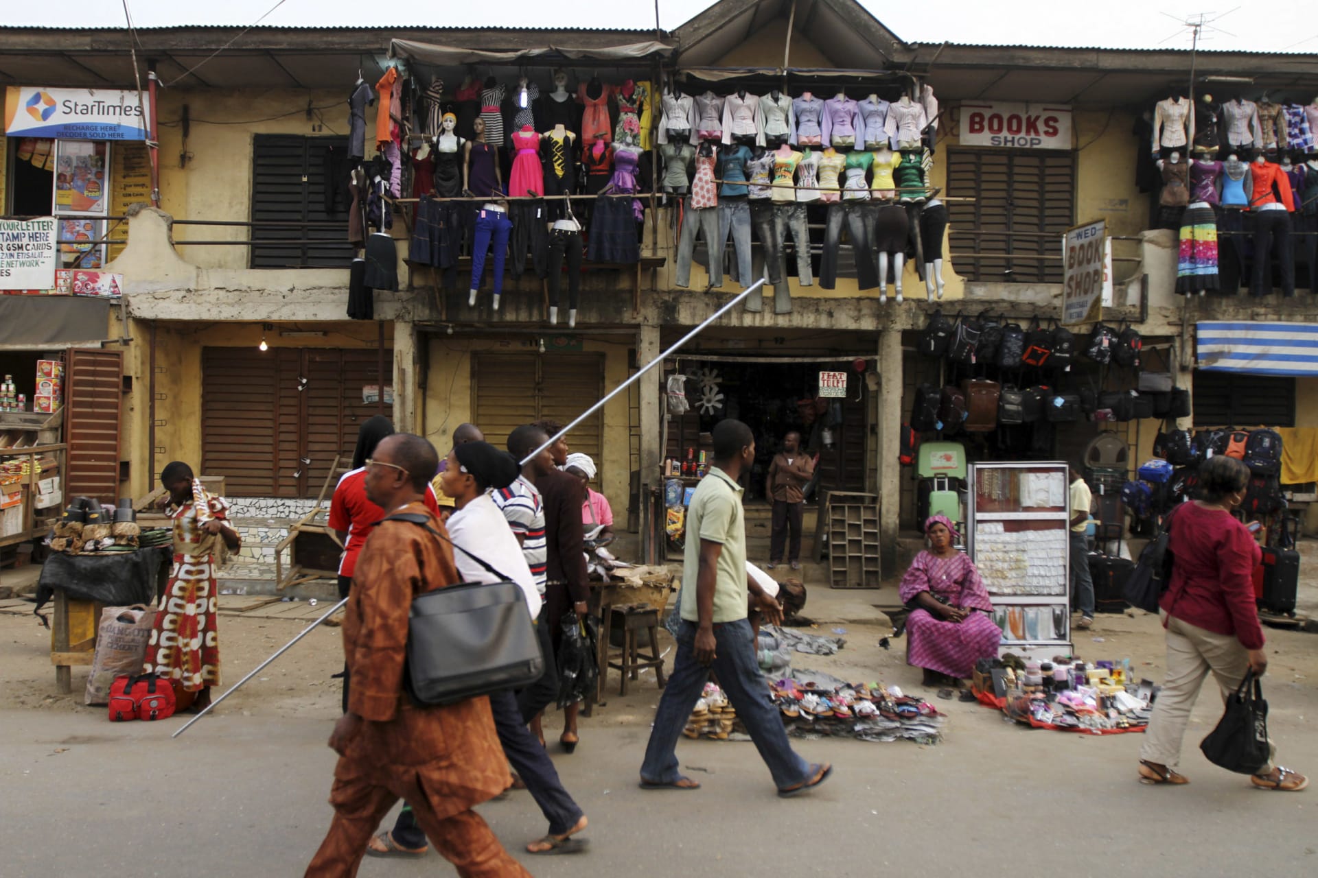 <p>People walk past market stalls in Nigeria’s commercial capital Lagos January 16, 2012.</p>
