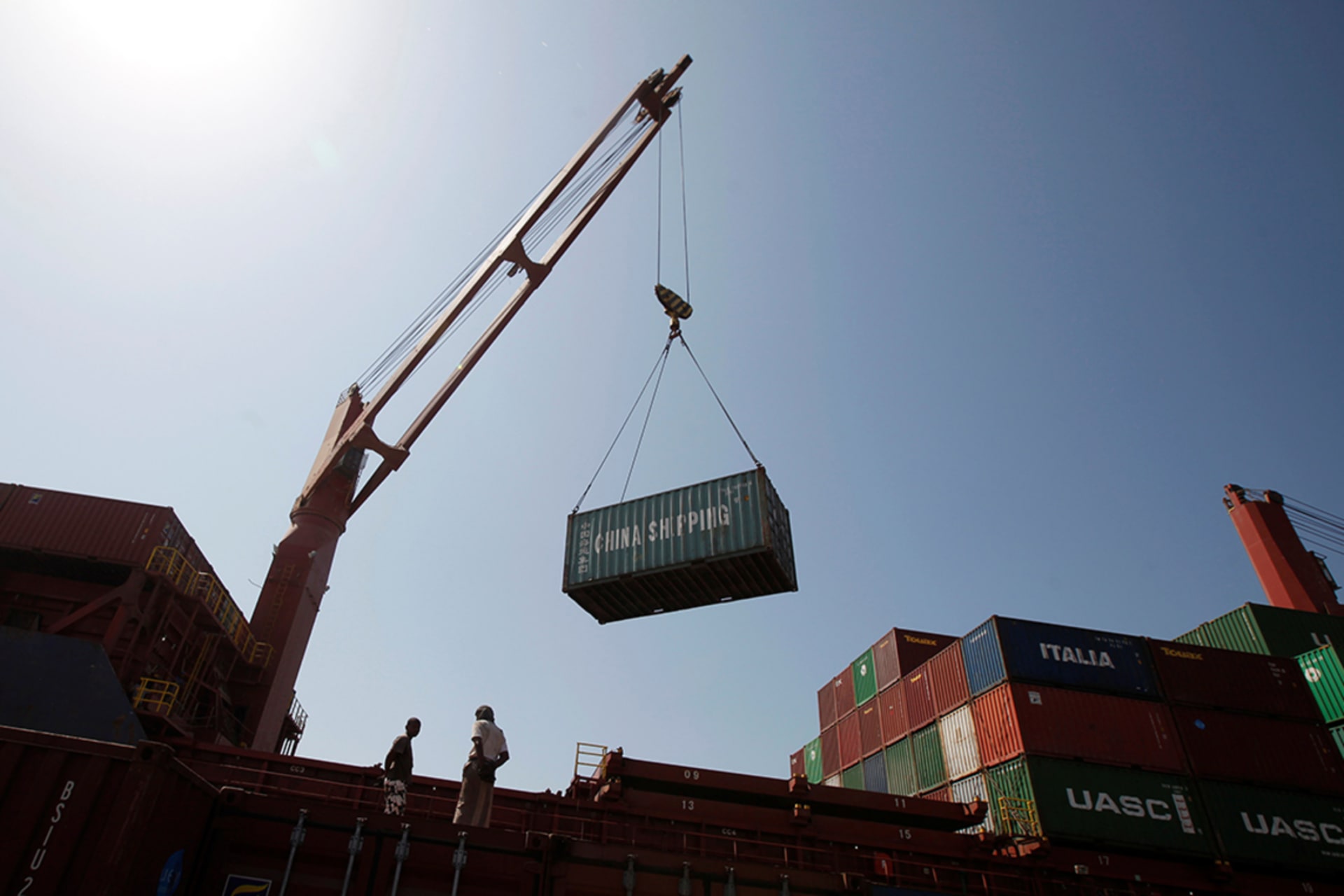 <p>Workers use a crane to unload shipping containers at a port in Yemen.</p>