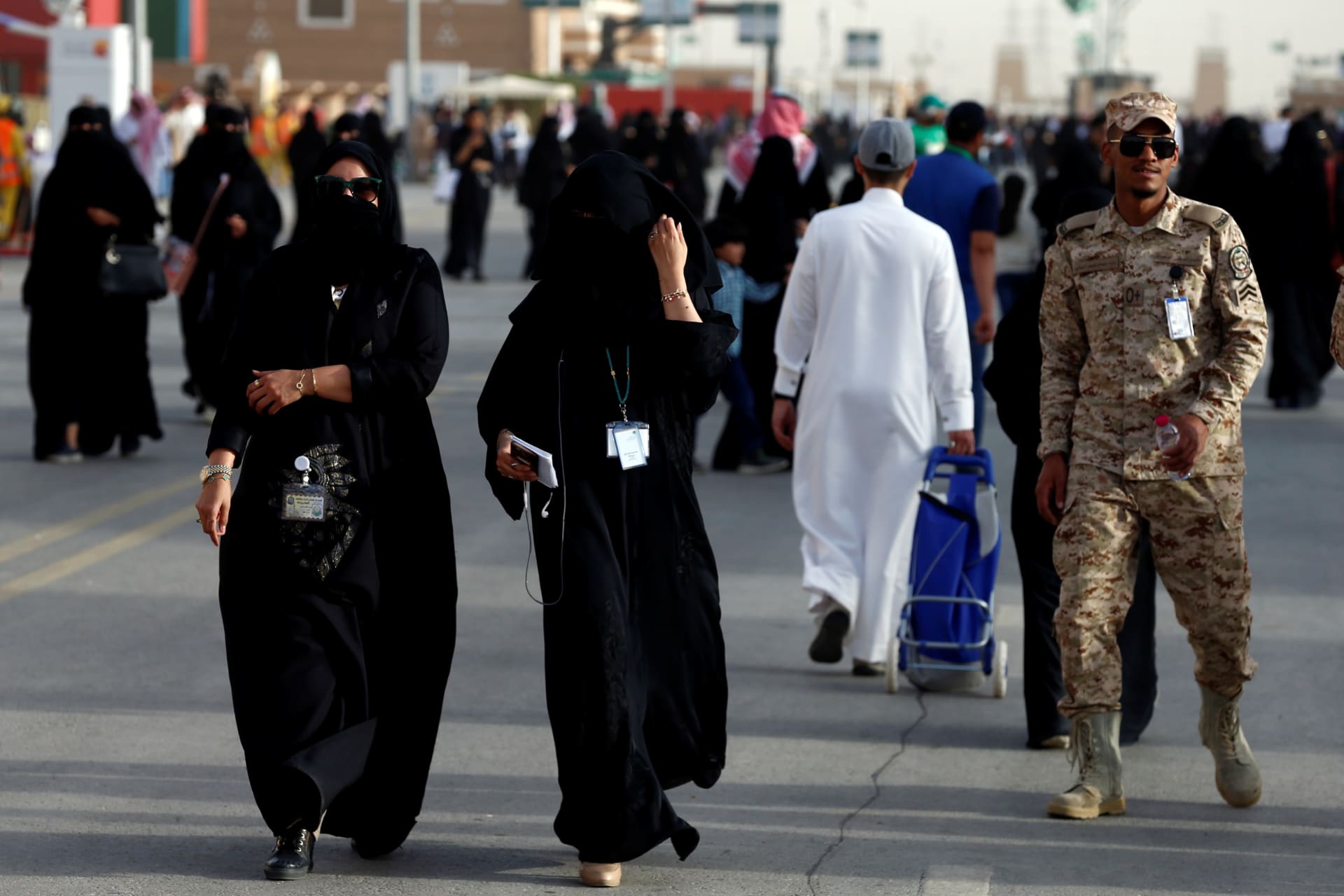 <p>Women pass by a member of Saudi security forces at the Janadriyah Cultural Festival on the outskirts of Riyadh, February 12, 2018. The Saudi government recently announced that women will be allowed to join the country’s armed forces.</p>
