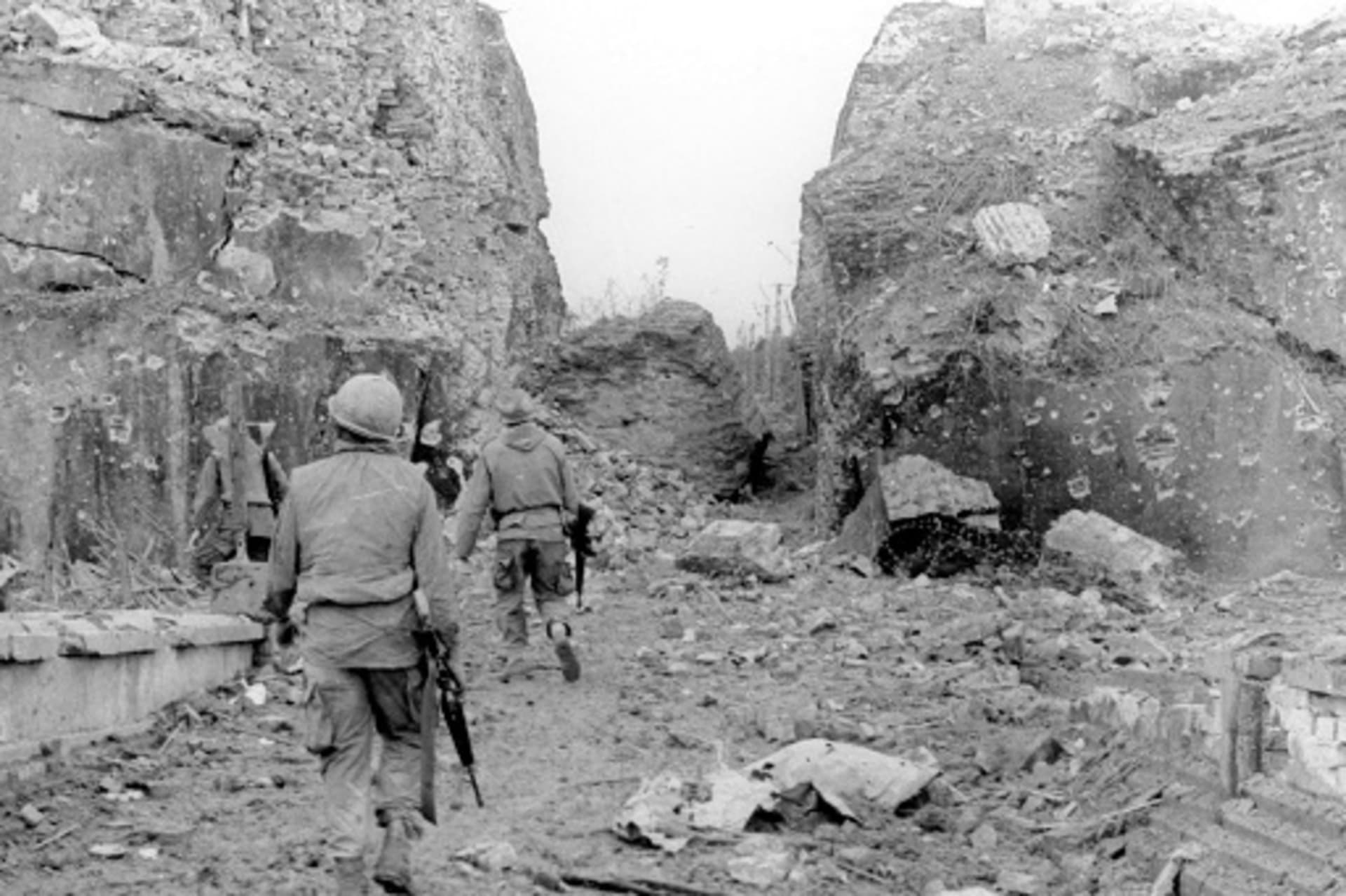 <p>U.S. soldiers of 5th Battalion, 7th Cavalry, pass through battered walls in Hue, during the Tet Offensive.</p>
