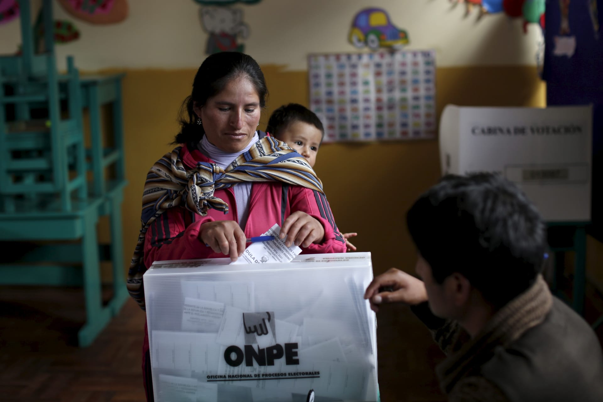 <p>A woman carrying her child casts her vote during general elections in the district of Poroy in Cuzco, Peru on April 10, 2016.</p>

