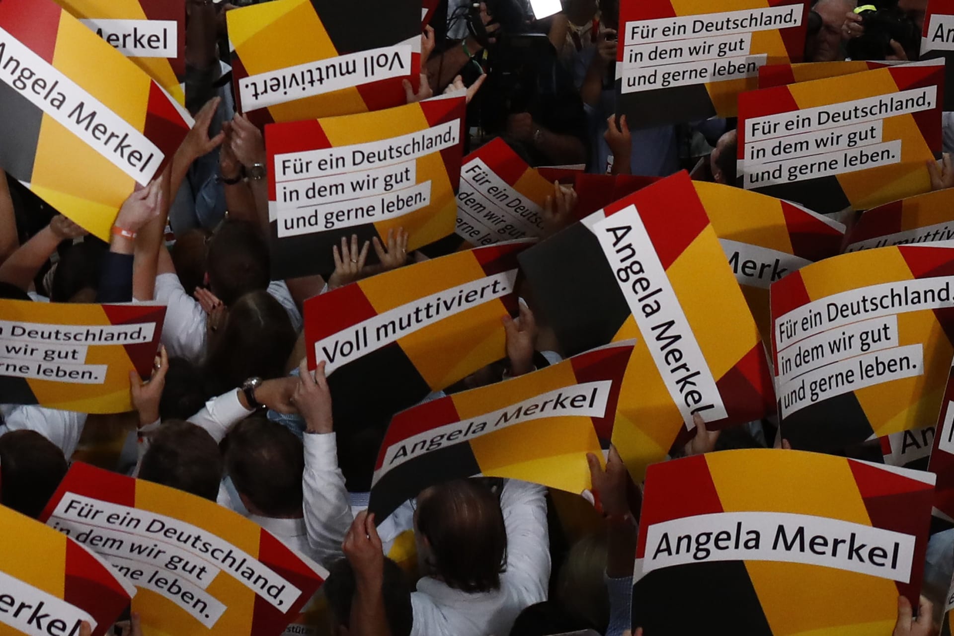 <p>People hold placards while waiting for Christian Democratic Union CDU party leader and German Chancellor Angela Merkel to react on first exit polls in the German general election (Bundestagswahl) in Berlin, Germany. </p>
