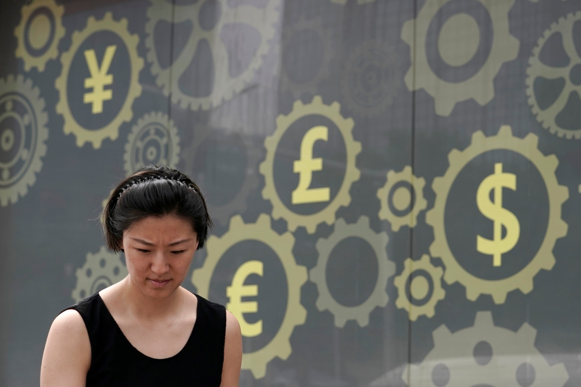 <p>A woman walks past the poster of a bank branch in Beijing, China.</p>
