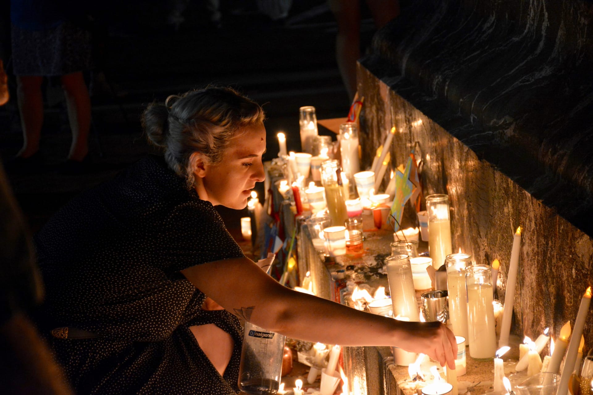 <p>A woman places a candle at a vigil for Heather Heyer at the University of Virginia. </p>
