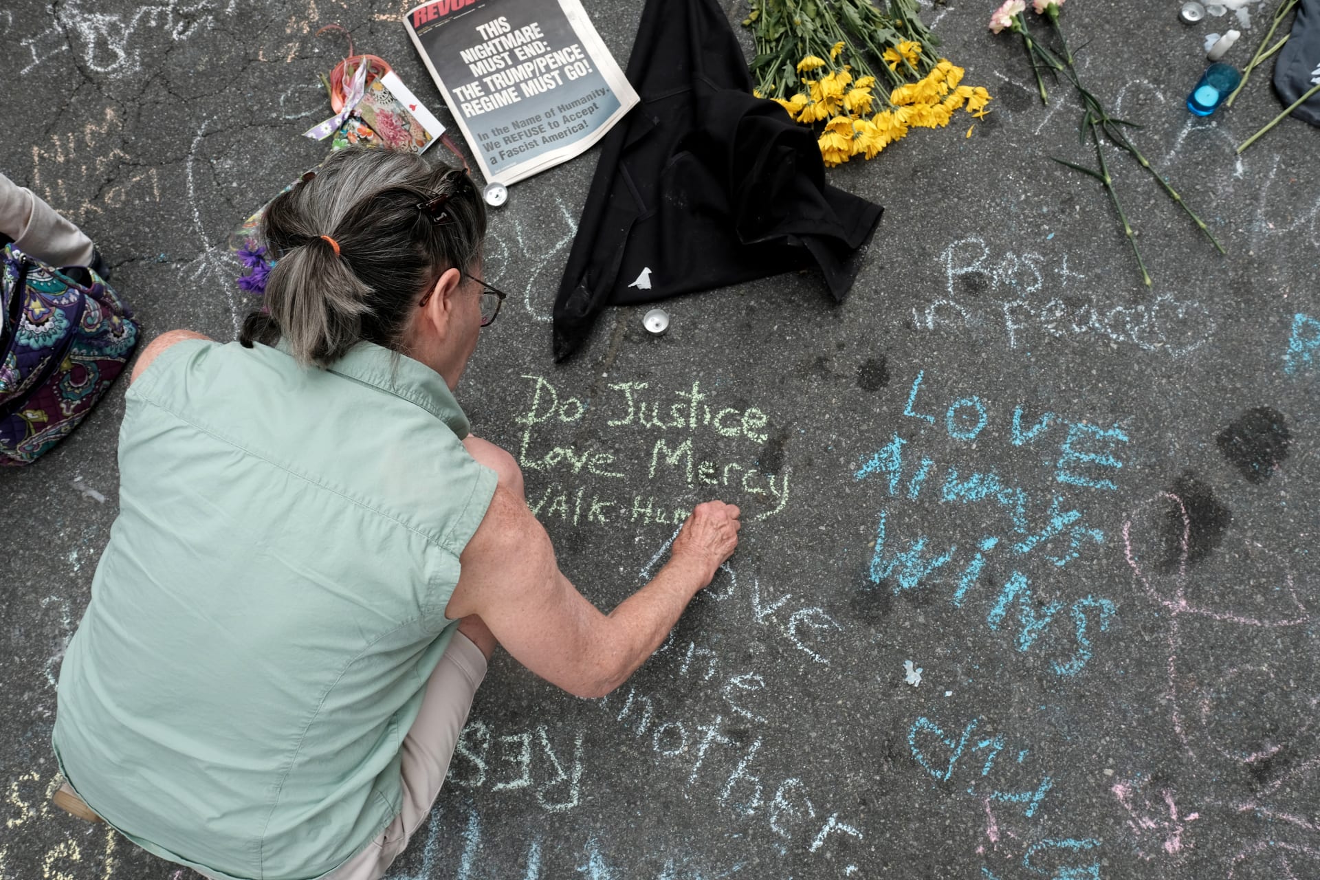 <p>A woman writes a message on the street commemorating the victims at the scene of the car attack on a group of counter-protesters during the “Unite the Right” rally in Charlottesville, Virginia on August 14, 2017.</p>
