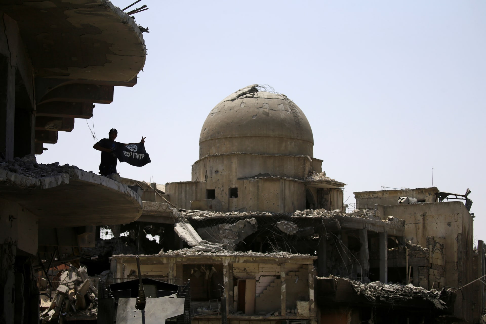 <p>A member of Iraqi security forces holds an upside-down Islamic State flag on top of a building destroyed from clashes in the Old City of Mosul, Iraq (Thaier Al-Sudani/Reuters).</p>
