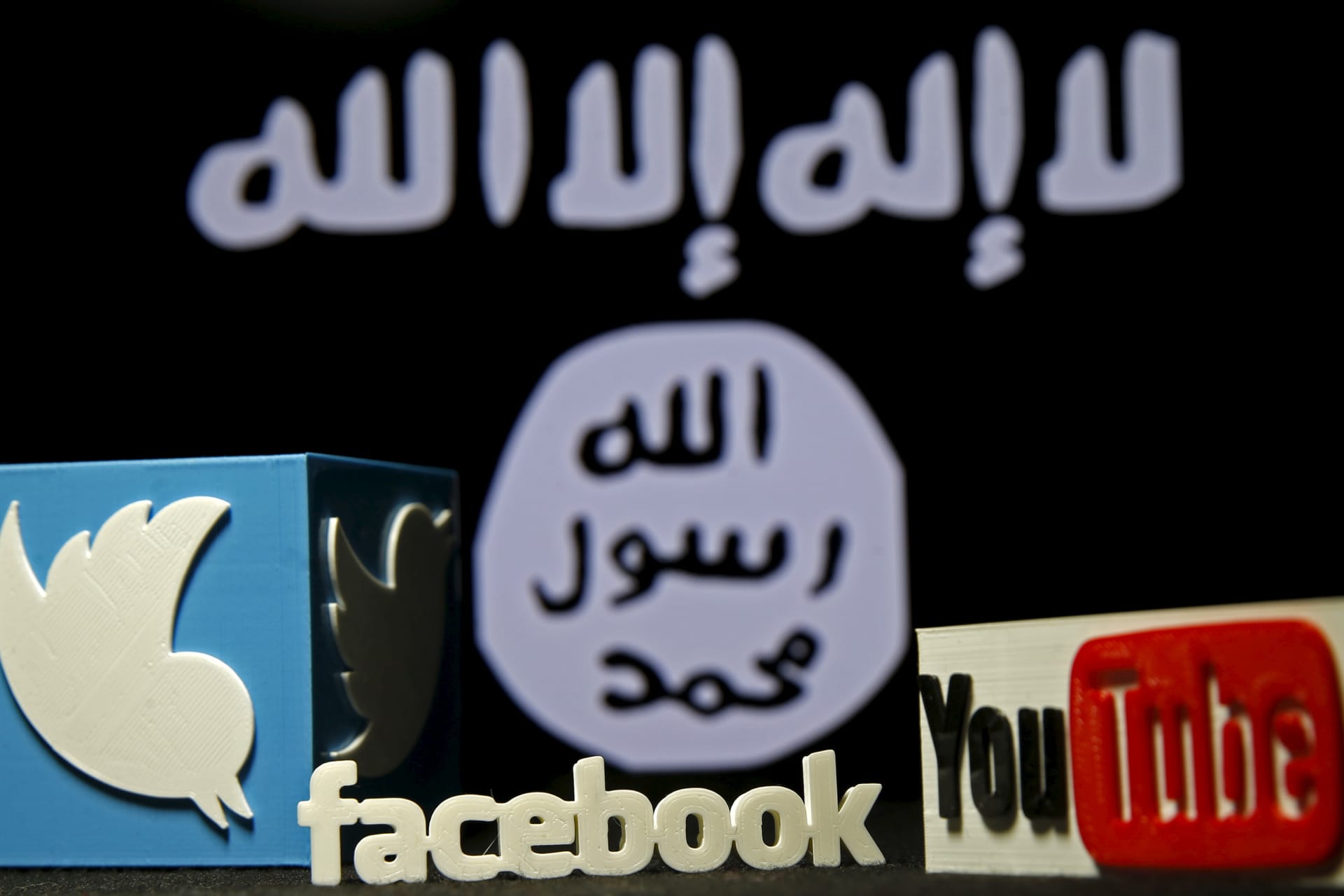 <p>A 3D plastic representation of the Twitter and Youtube logo is seen in front of a displayed Islamic State group flag in this photo illustration.</p>
