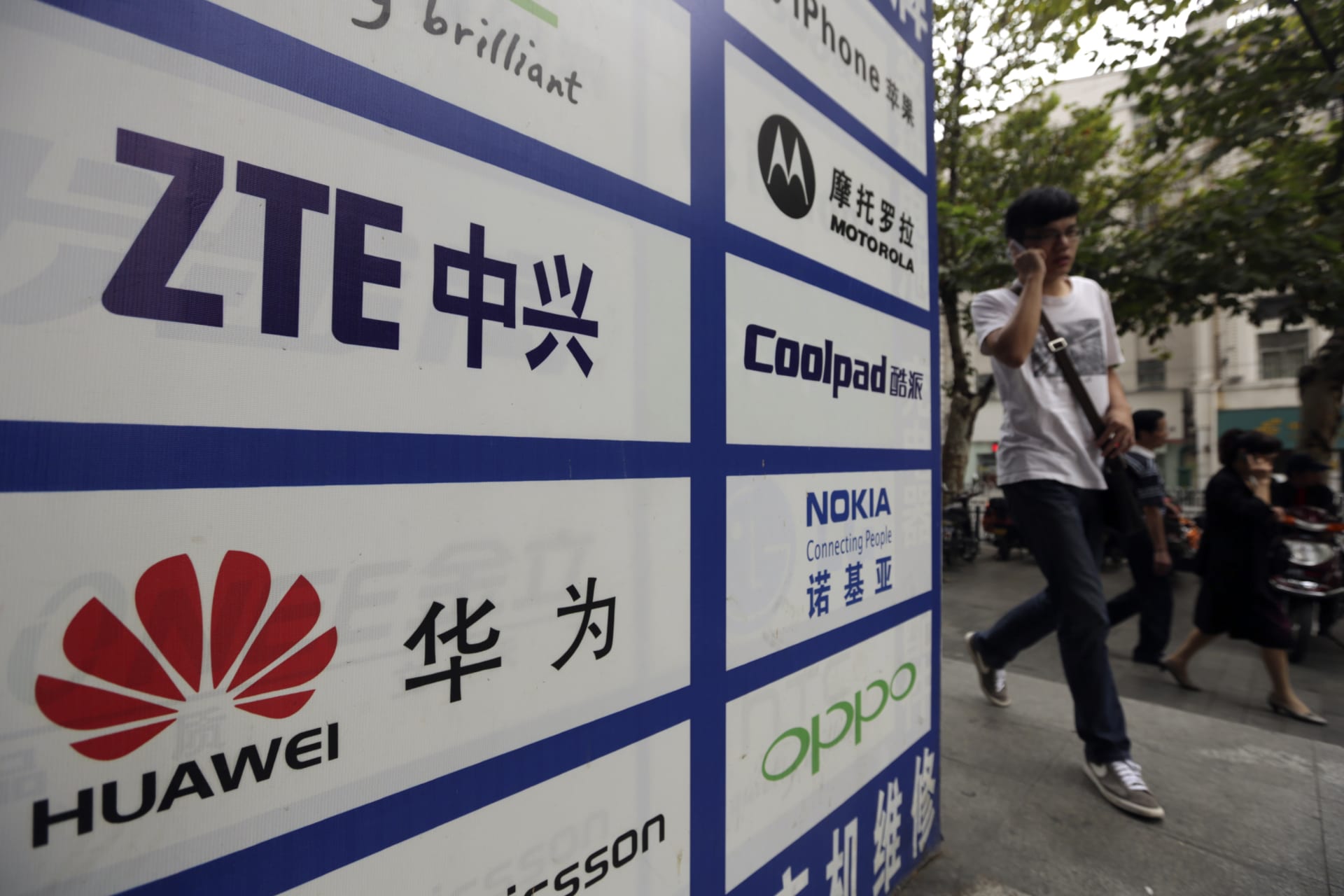 <p>A man walks past an advertisement board showing the logos of Huawei and ZTE outside a mobile phone repair shop in Wuhan, China. Huawei and ZTE have been active participants in building the digital new silk road.</p>
