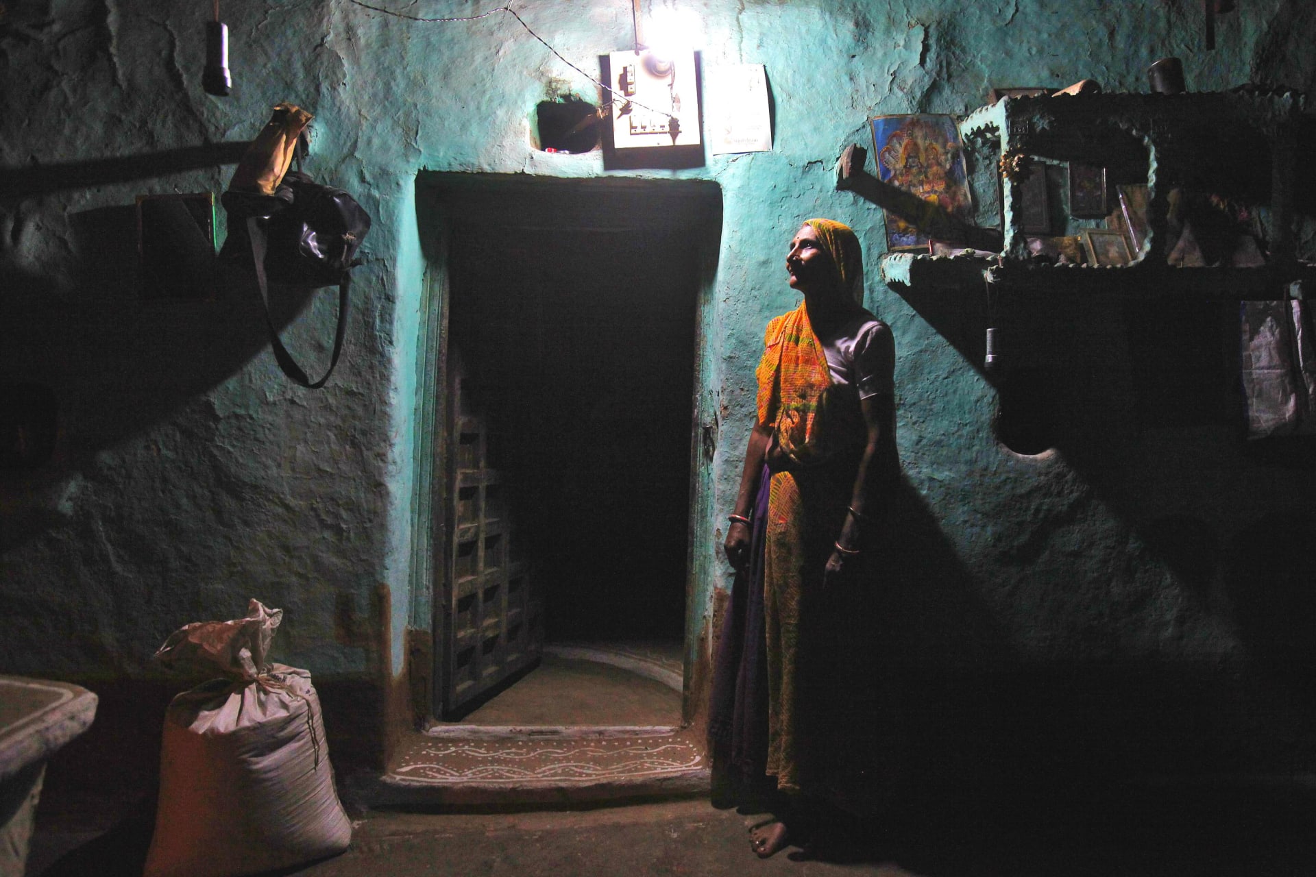 <p>Sampat Bai stands inside her house illuminated by a compact fluorescent lamp powered by solar energy, in the central Indian state of Madhya Pradesh.</p>
