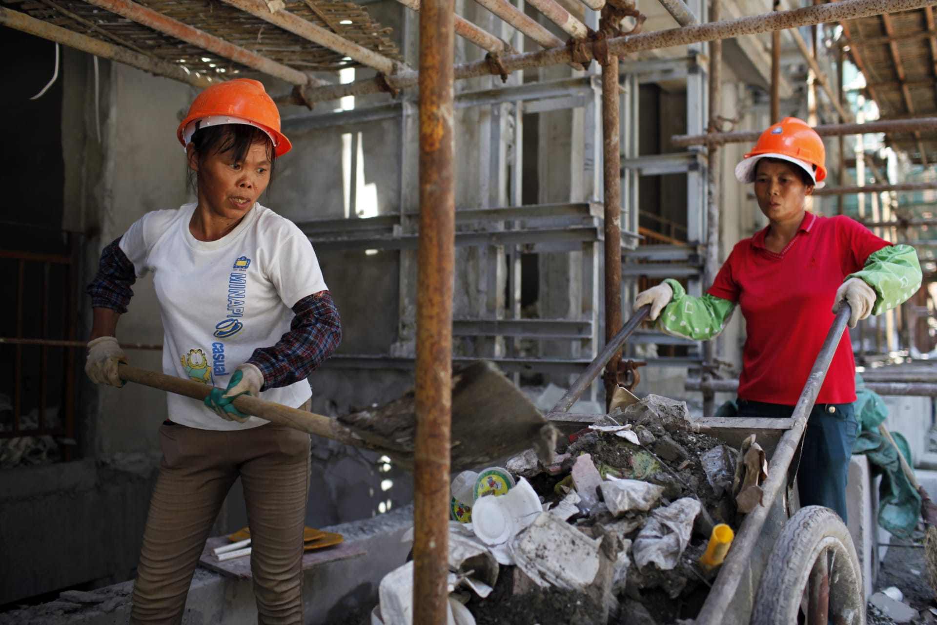 <p>Female migrant construction workers collect garbage onto a cart as they work on a shift at a residential construction site in Shanghai August 12, 2013.</p>
