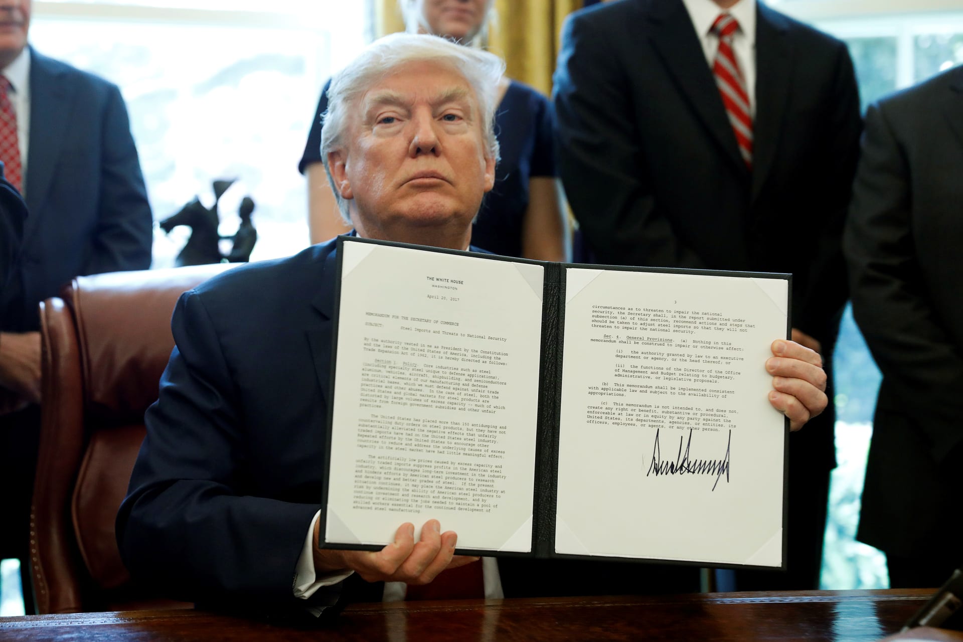 <p>U.S. President Donald Trump holds up a directive ordering an investigation into the impact of foreign steel on the American economy after signing it.</p>
