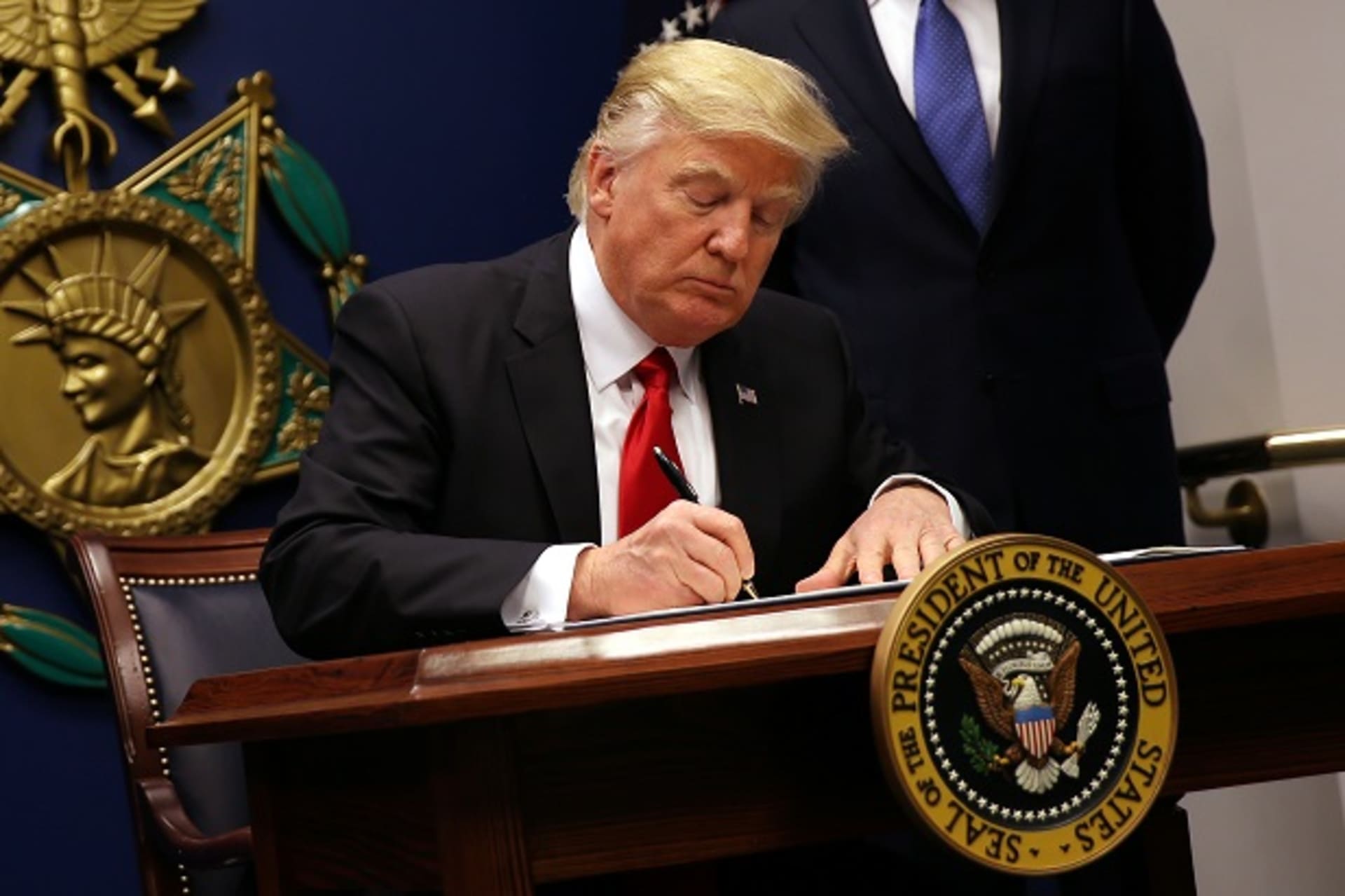 <p>President Donald Trump signs an executive order imposing tighter vetting on travelers entering the United States. (Photo: Reuters/Carlos Barria)</p>
