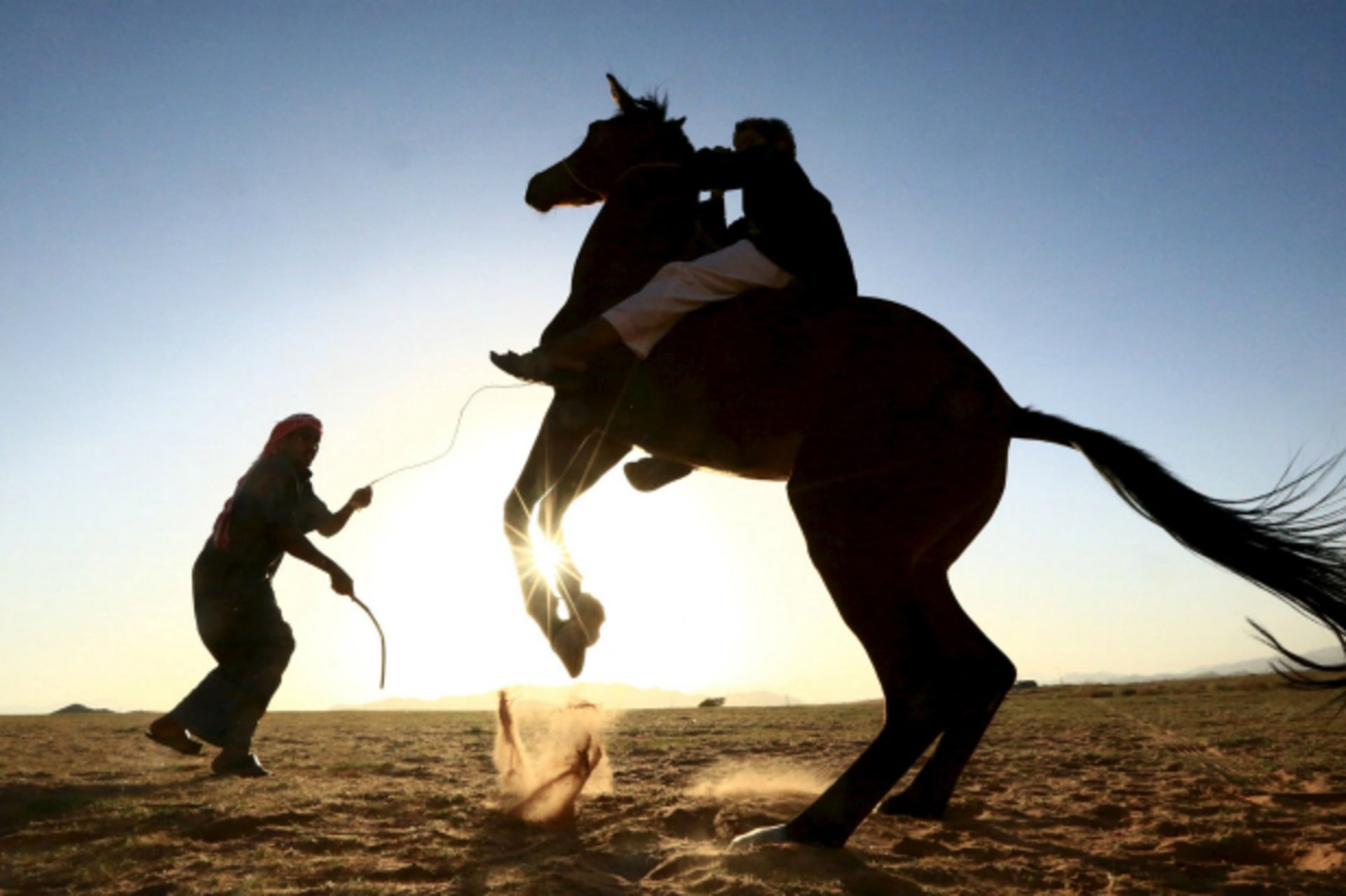 <p>A Saudi man trains his son to ride a horse in a desert near Tabuk, Saudi Arabia (Mohamed Al Hwaity/Reuters).</p>

