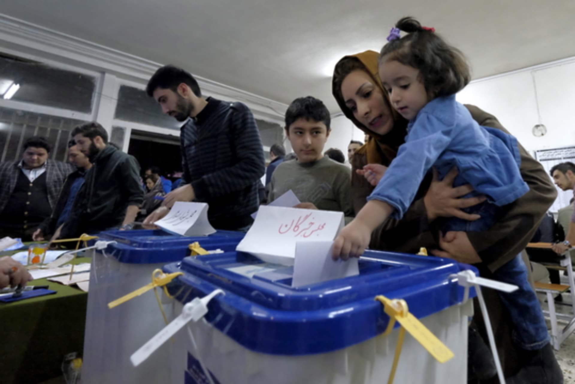 Iranian woman holding her daughter casts her ballot during elections for the parliament and Assembly of Experts, in Tehran