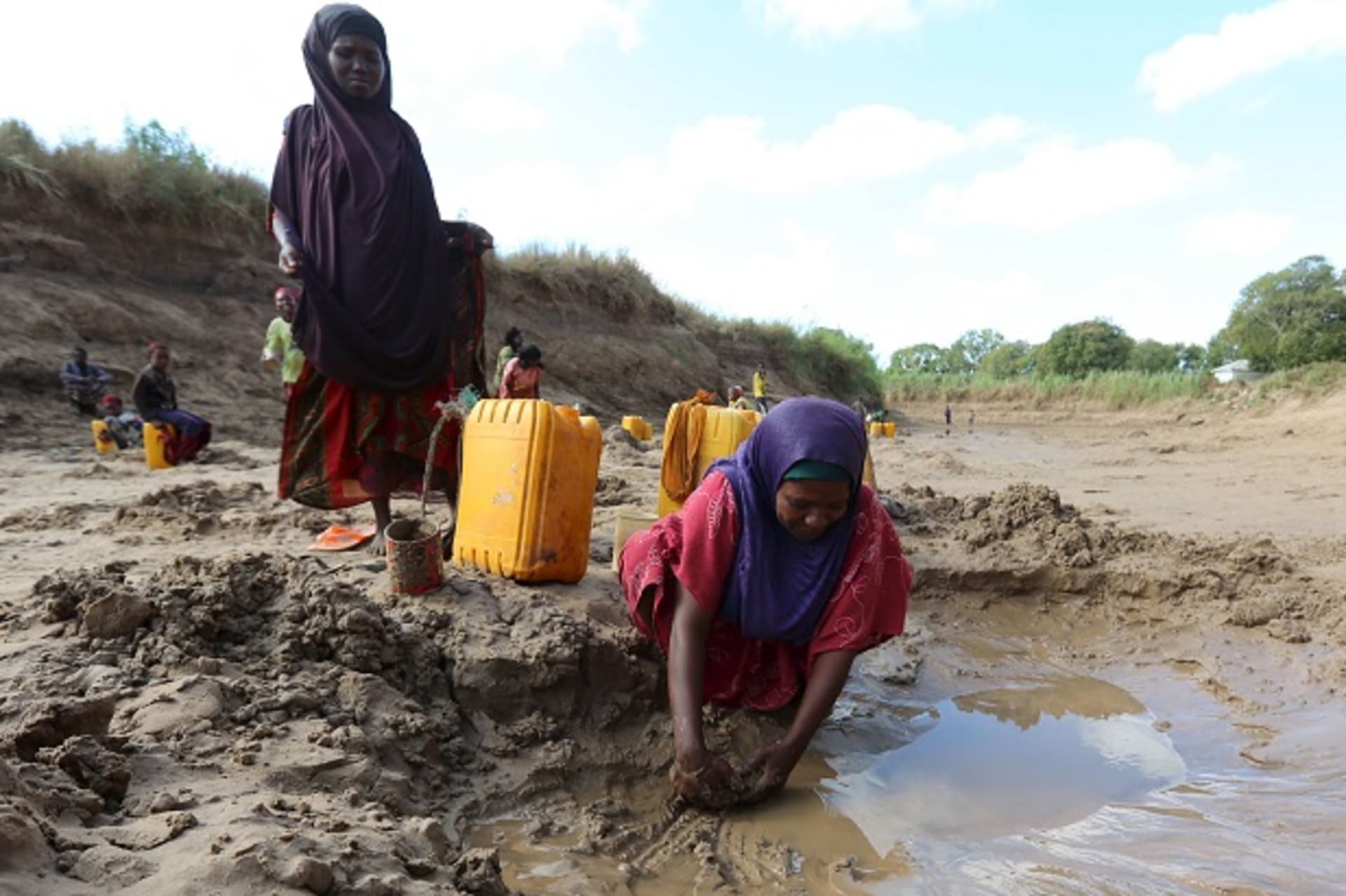 People collect water from shallow wells dug along the Shabelle River bed, which is dry due to drought in Somalia's Shabelle region