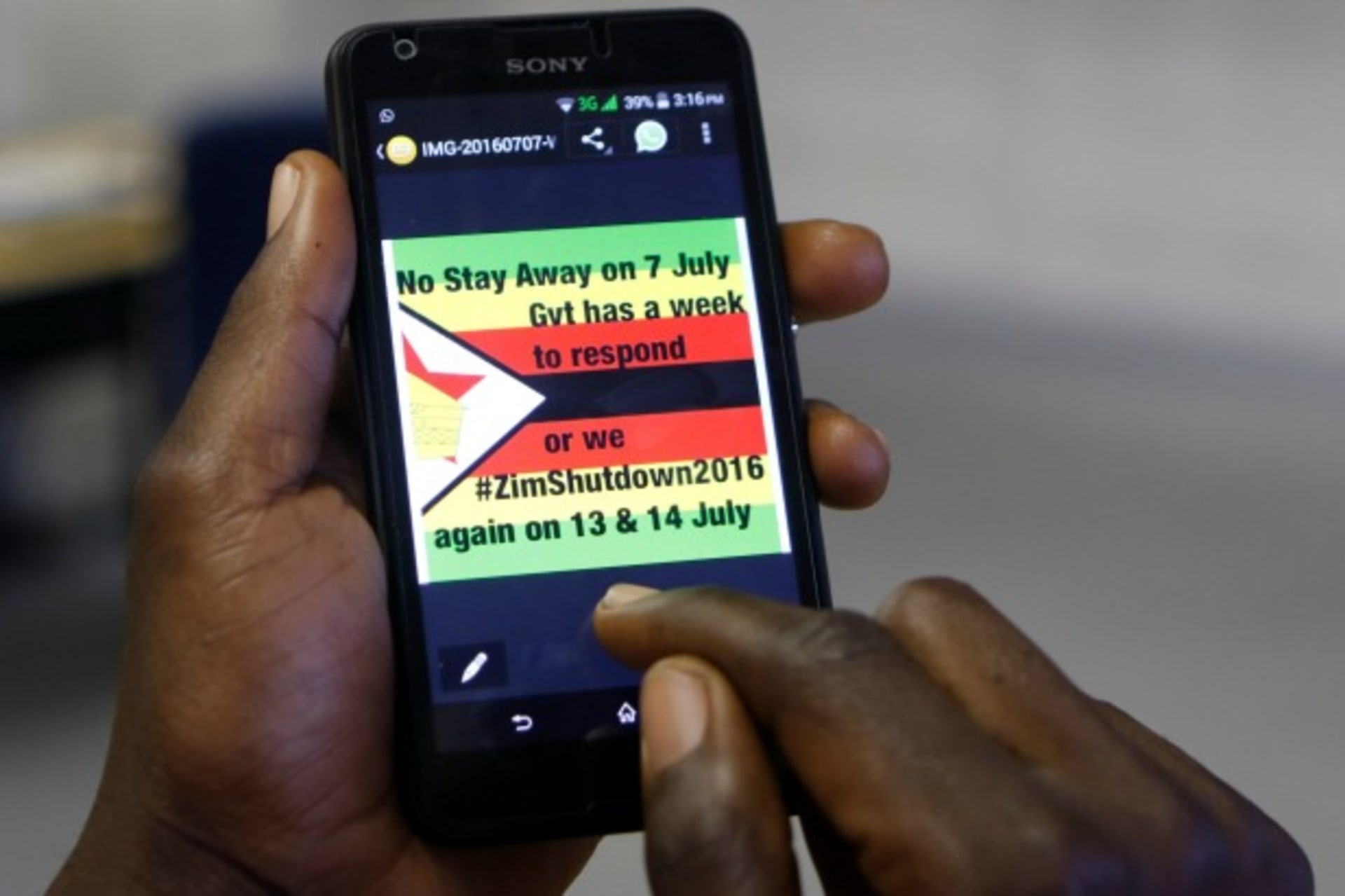 <p>A man checks a message on his mobile phone, in Harare, Zimbabwe, July 7, 2016 (Reuters/Philimon Bulawayo).</p>
