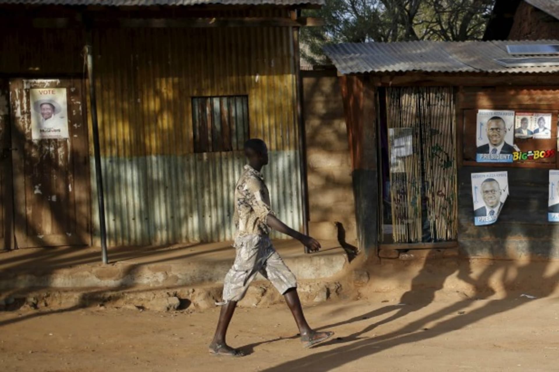 <p>A man passes by a poster of Uganda’s President Yoweri Museveni and a poster of opposition leader Kizza Besigye in town of Kaabong in Karamoja region, Uganda, February 17, 2016 (Reuters/Goran Tomasevic).</p>
