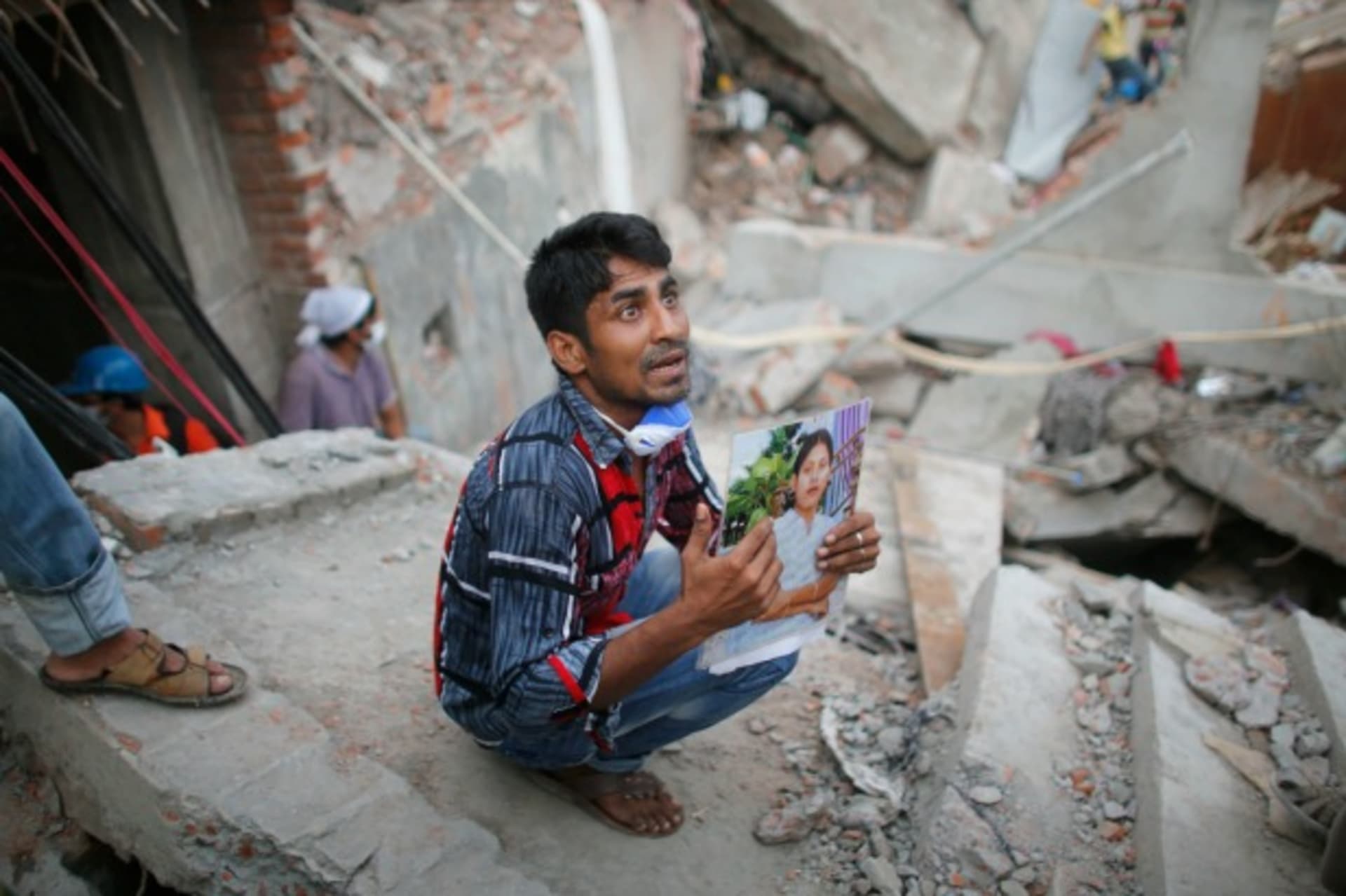 <p>A relative holds up a picture of a garment worker in front of the rubble of the collapsed Rana Plaza building (Reuters/Andrew Biraj).</p>
