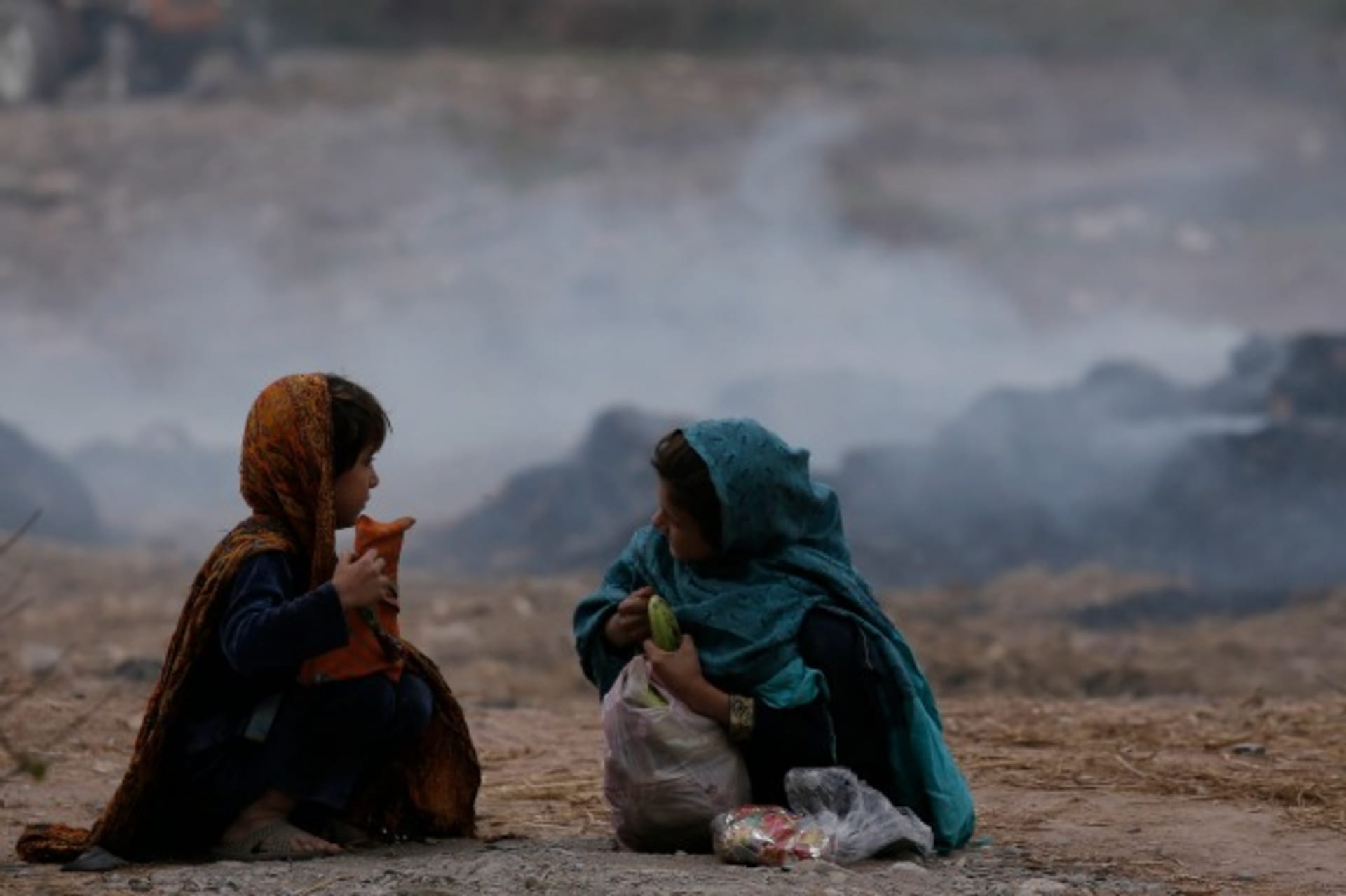 <p>Girls sit near a dumping ground in Peshawar (Reuters/A. Ali).</p>
