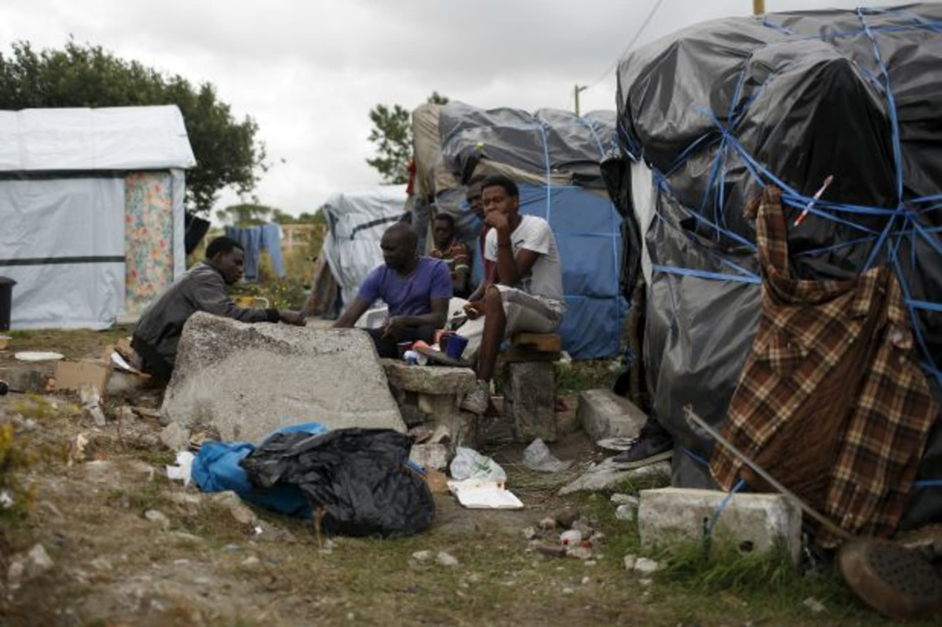 <p>Sudanese migrants stand at “The New Jungle” camp in Calais, France, August 6, 2015. For most of the 3,000 inhabitants of the “…ach day is the nightly bid to sneak into the undersea tunnel they hope will lead to new life in Britain (Juan Medina/Reuters).</p>
