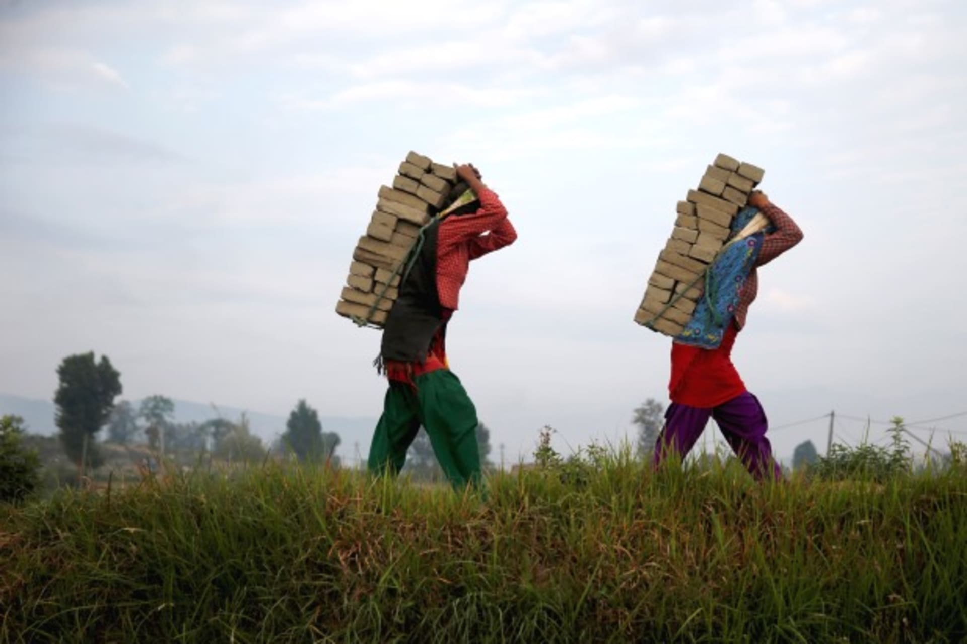 <p>Women carry bricks on their back as they work at a brick factory in Bhaktapur, Nepal. (Courtesy Ahmad Masood/Reuters)</p>
