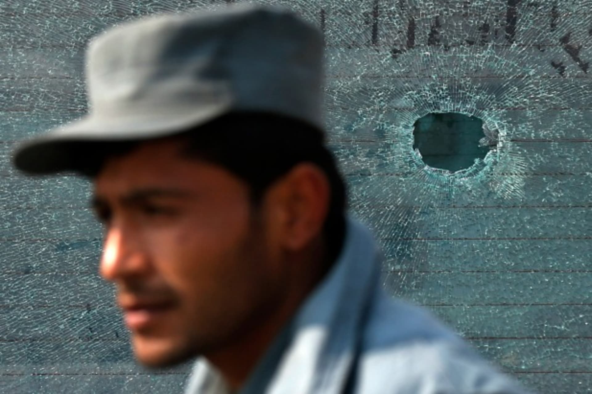 <p>A policeman stands in front of a car window, which has been hit by a bullet, after clashes with protesters in Kabul, Afghanistan, January 31, 2015 (Courtesy Mohammad Ismail/Reuters).</p>
