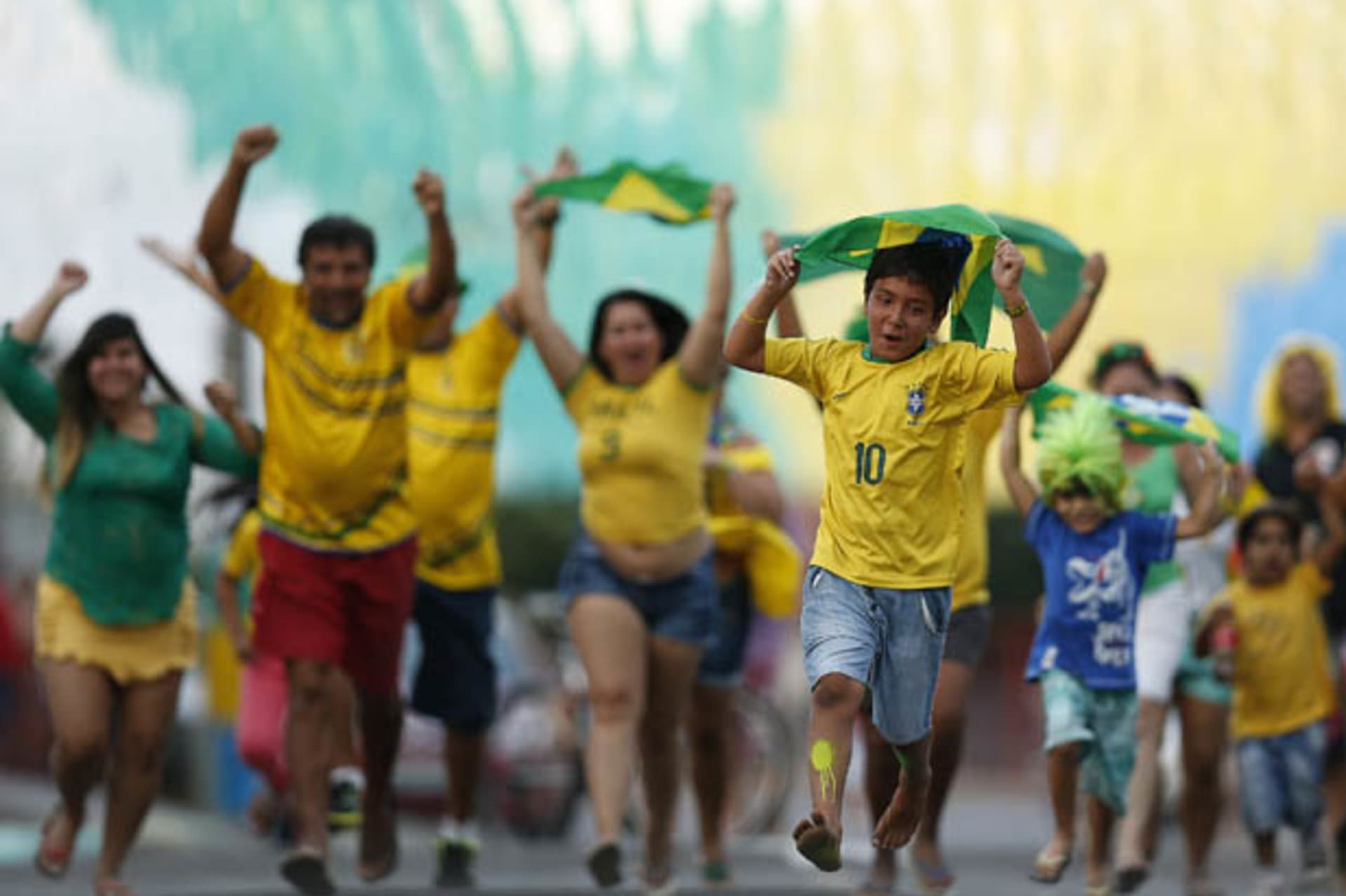 Residents run to celebrate after decorating a street in the colours of Brazil's national flag, ahead of the 2014 World Cup, in the Taguatinga neighbourhood of Brasilia