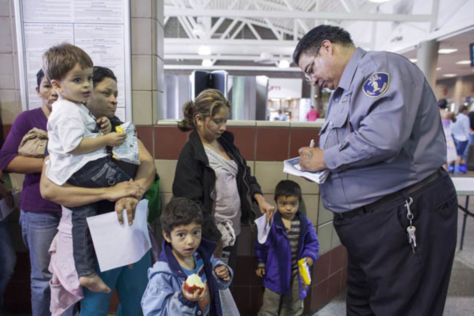 Migrants who just disembarked from a U.S. ICE bus wait for a Greyhound official to process their tickets to their next destination at a Greyhound bus station in Phoenix