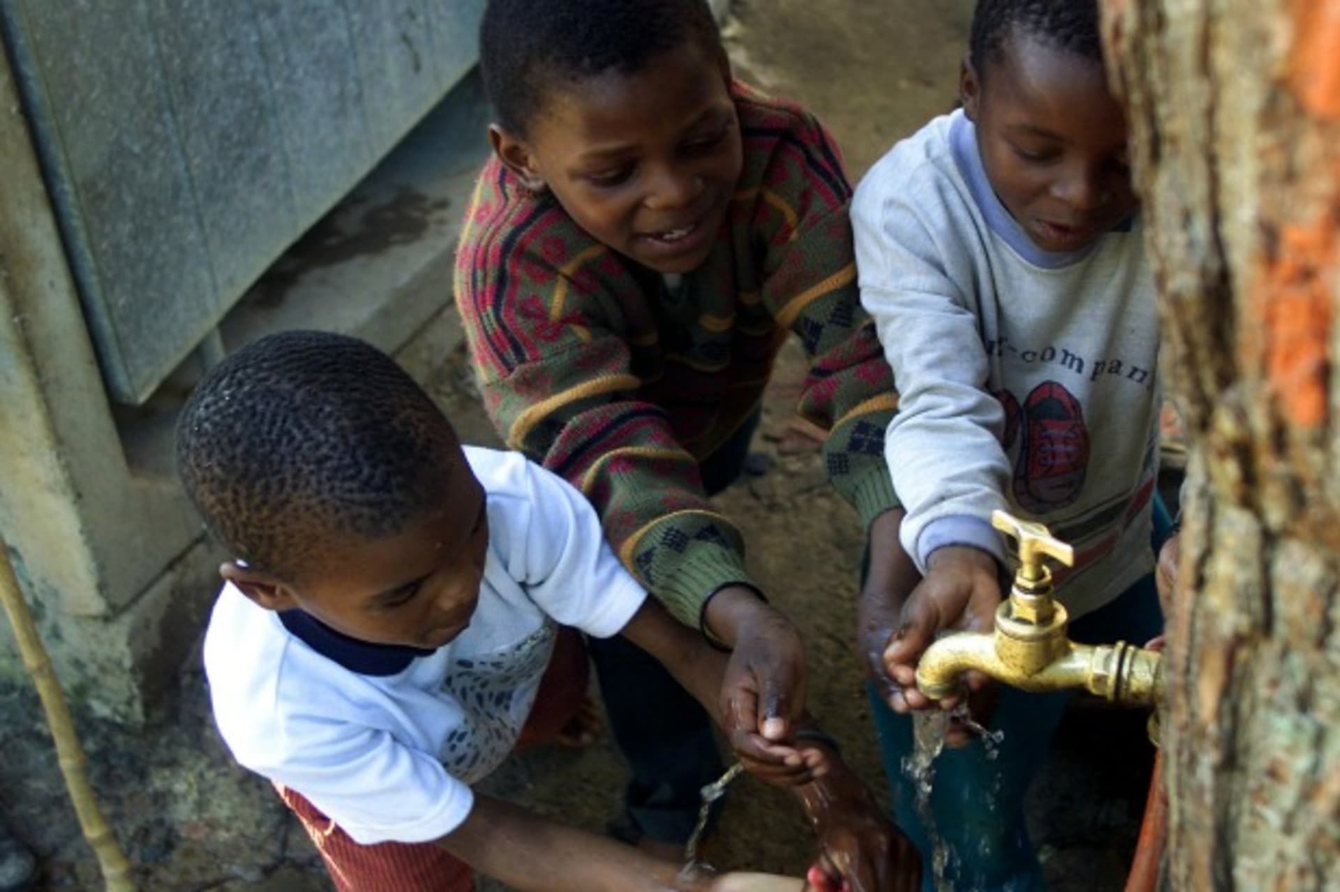 <p>Children play around a communal tap servicing the Imizamo Yethu community near Cape Town, South Africa, August 2002 (Courtesy Reuters/ Mike Hutchings).</p>
