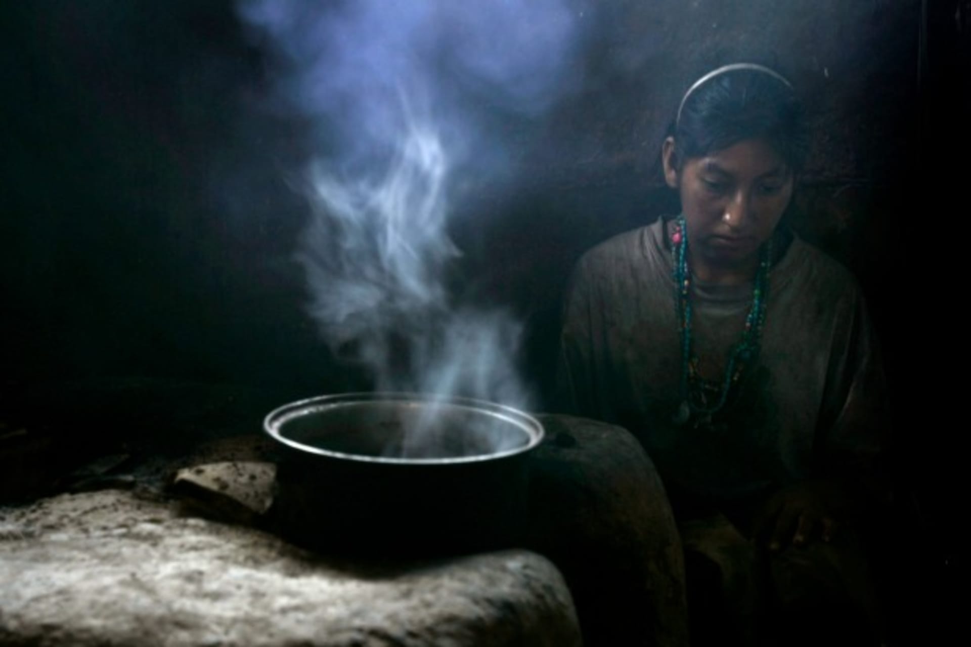 <p>A woman cooks inside her home in San Juan, Honduras, August 2008 (Courtesy Reuters/Edgard Garrido).</p>