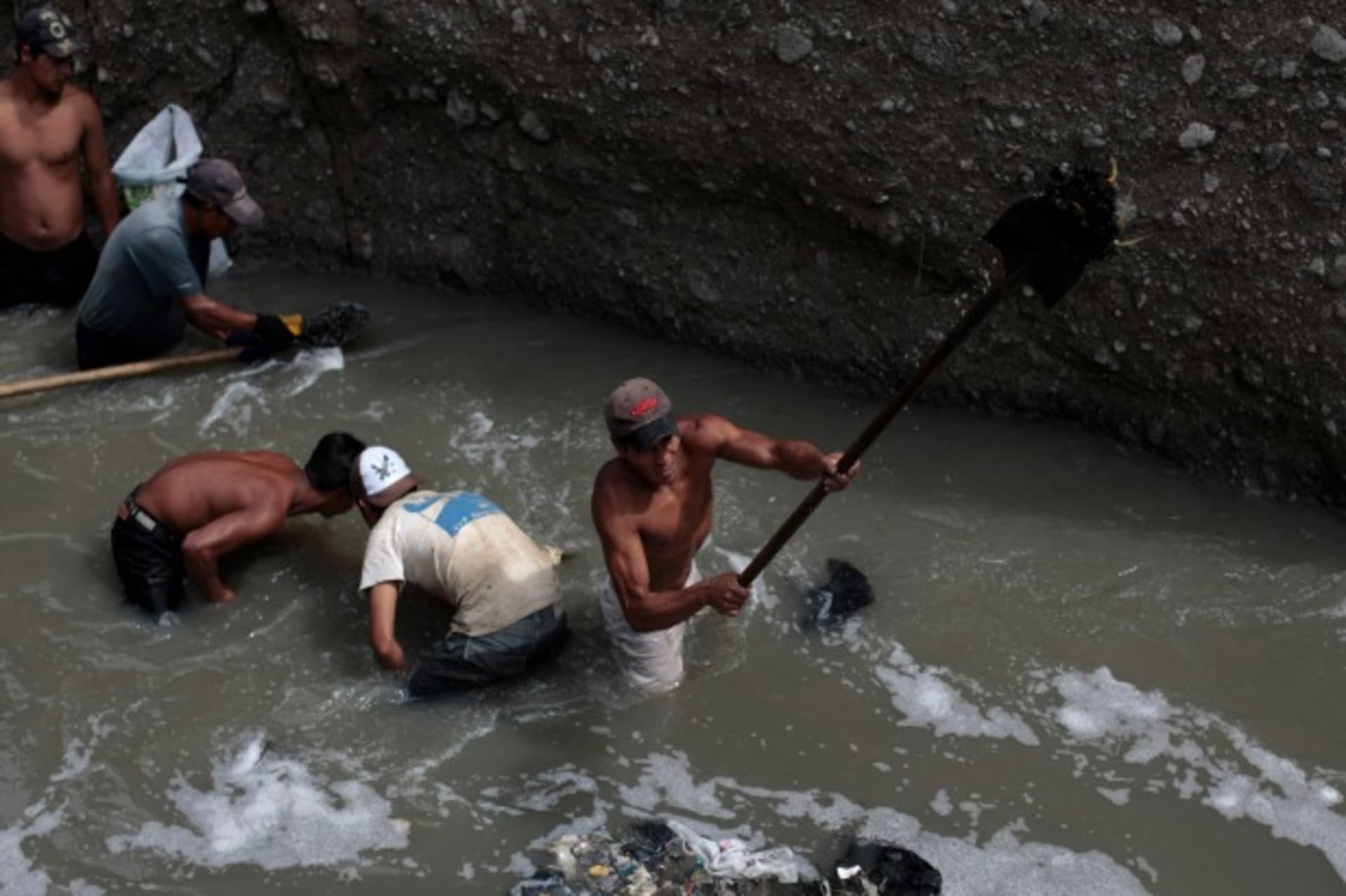 <p>Men look for metals and other valuables in the waste waters of the city dump in Guatemala City, Guatemala, September 2011 (Courtesy Reuters/Jorge Dan Lopez).</p>

