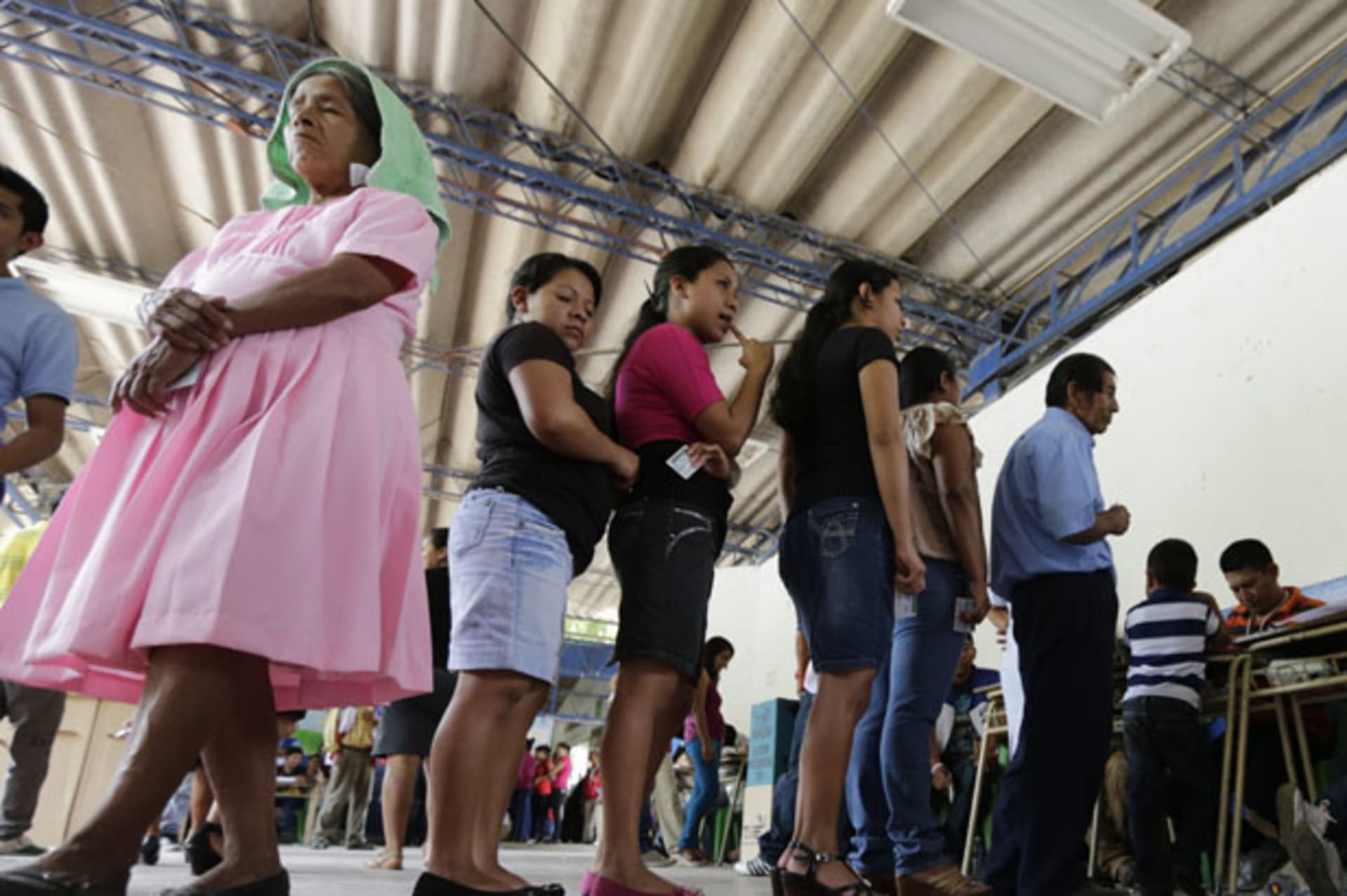 Voters wait in line to cast their vote in a presidential election runoff at a polling station outside in San Salvador