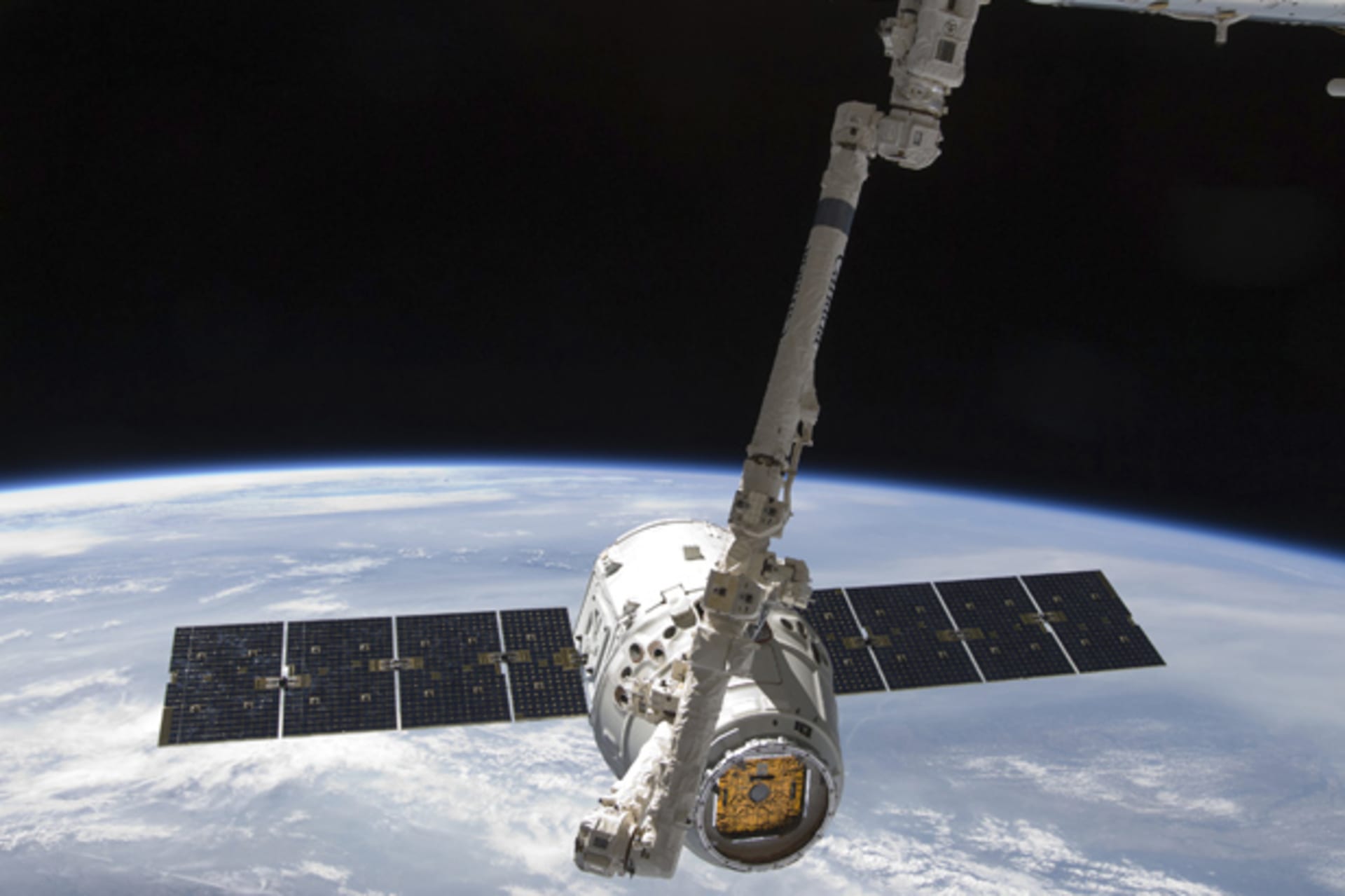 With the Earth in the background, the SpaceX Dragon commercial cargo craft is seen as it is grappled by the International Space Station's Canadarm2 robotic arm (Photo provided by NASA/Courtesy Reuters).
