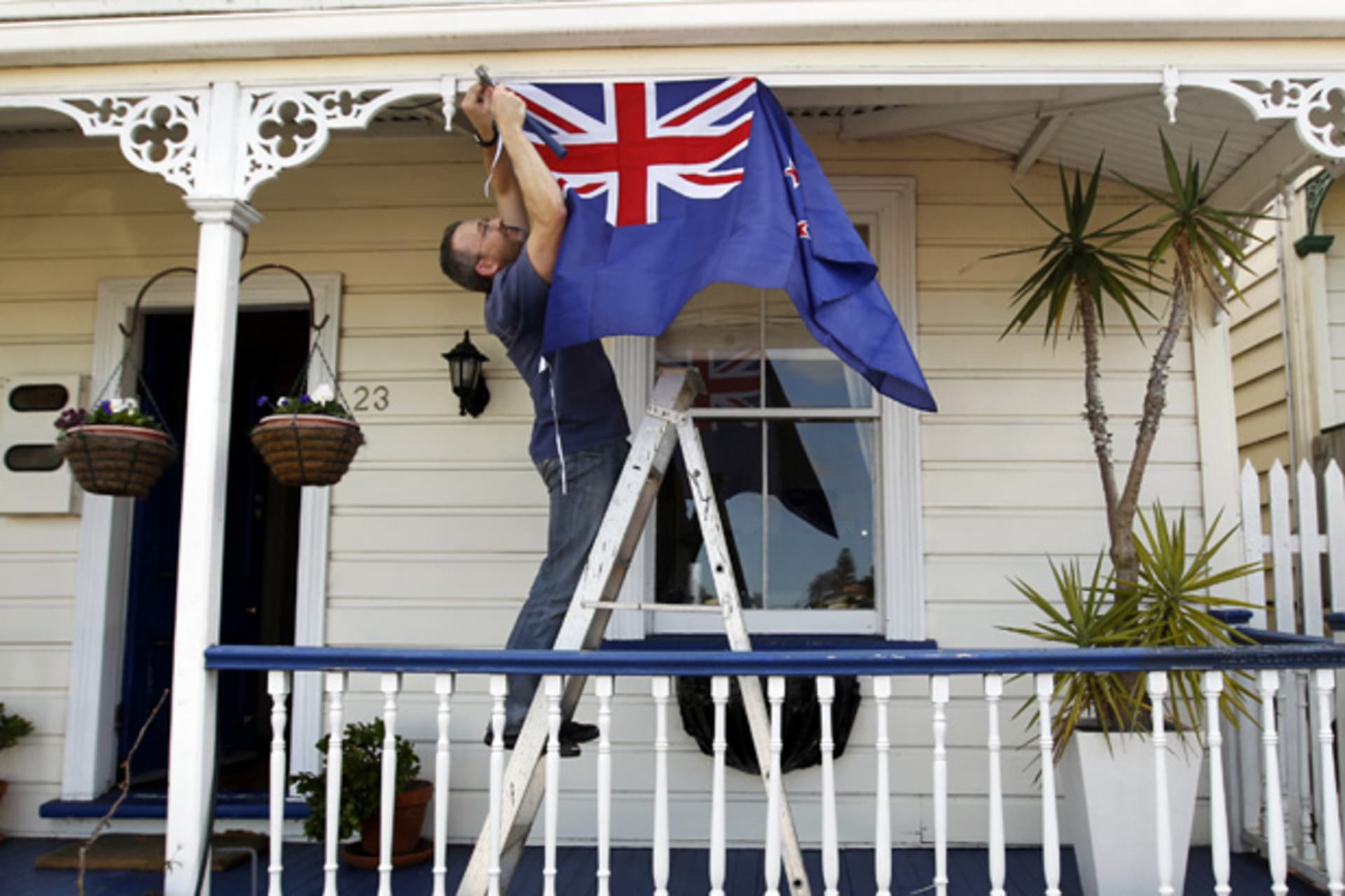 <p>New Zealand resident Brett Plumer nails a national flag to his house in Auckland (Bogdan Cristel/Courtesy Reuters).</p>
