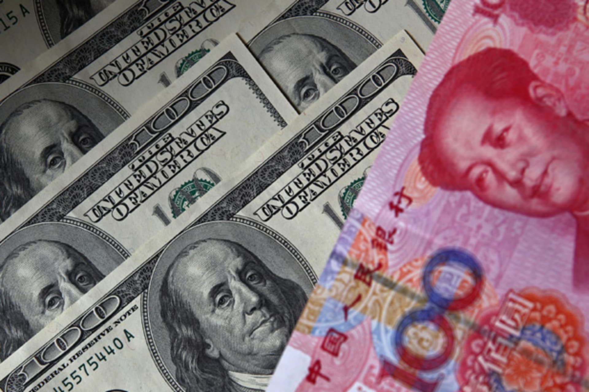 A 100 yuan banknote is placed next to $100 banknotes (Petar Kujundzic/Courtesy Reuters).