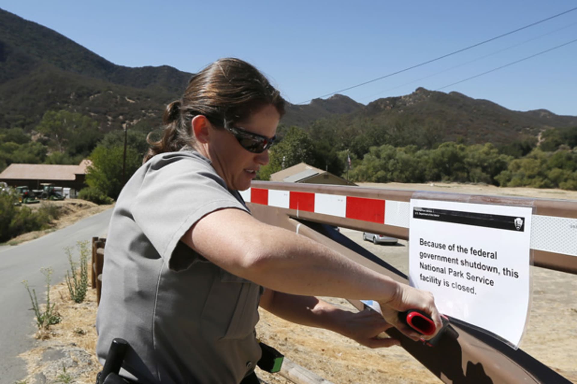 <p>U.S. Park Ranger Melanie Turner posts a sign on the gate of the Paramount Ranch to close the National Park Service site at the Santa Monica Mountains in California (Lucy Nicholson/Courtesy Reuters).</p>

