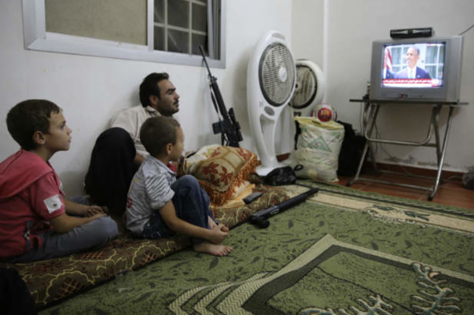 A Free Syrian Army fighter watches U.S. President Barack Obama's speech with his family in Ghouta, Damascus August 31, 2013 (Abdullah/Courtesy Reuters).