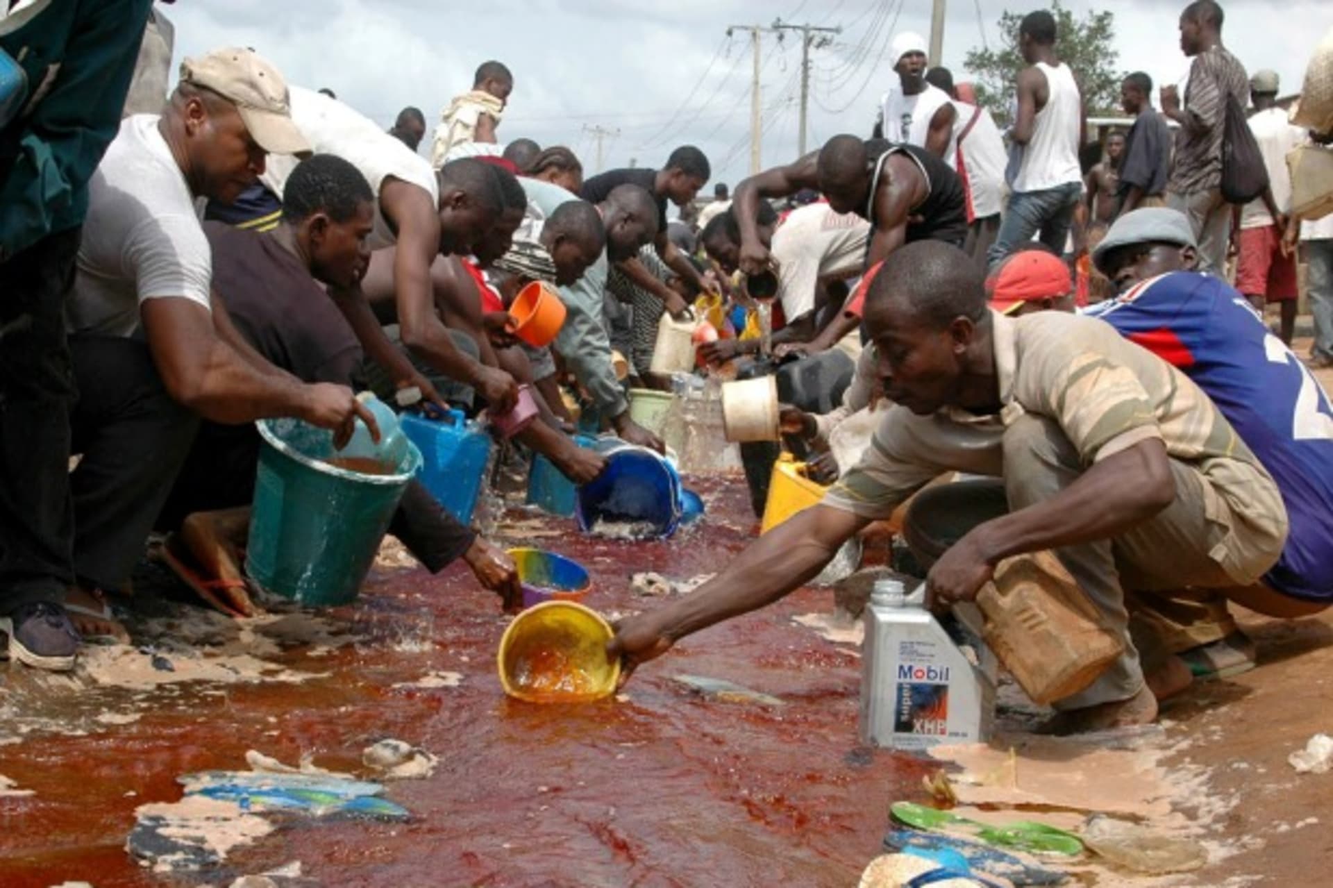 <p>Nigerians scoop petrol after a Nigerian National Petroleum Corporation pipeline burst in April 2006 (Courtesy Reuters).</p>

