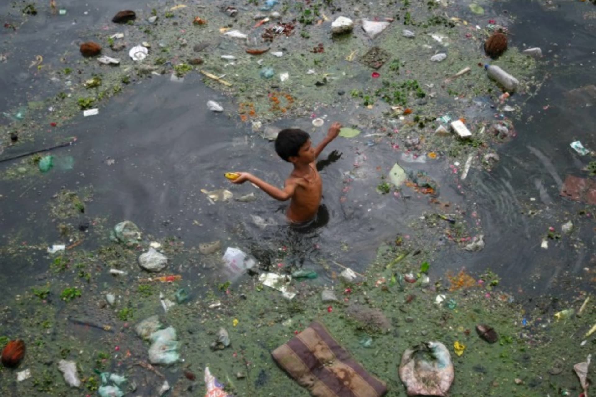 <p>A boy wades through polluted waters in Ahmedabad, India, July 2013 (Courtesy Reuters/Amit Dav).</p>
