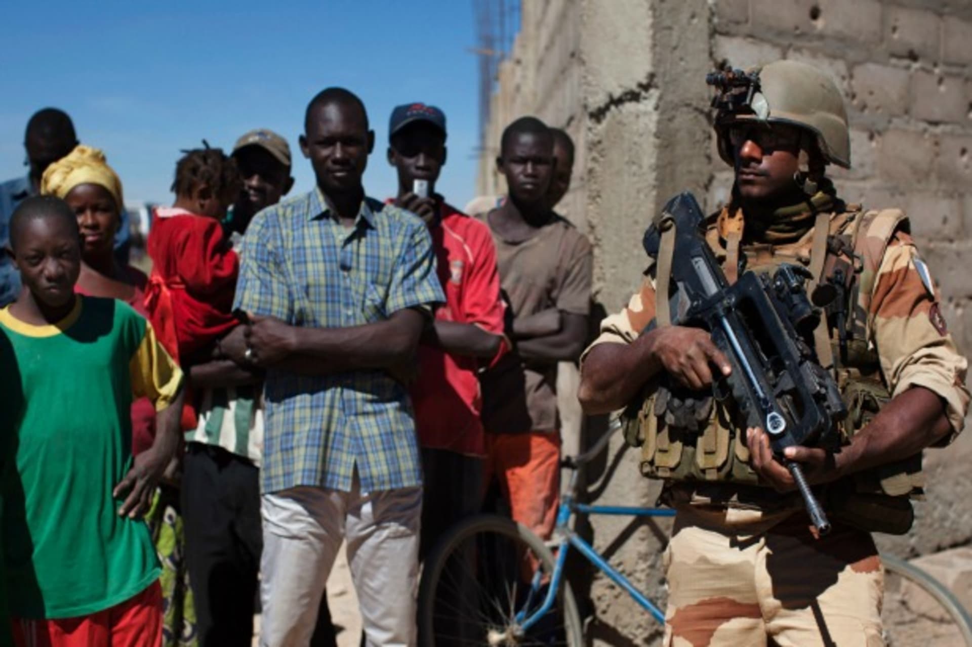 <p>A French soldier stands guard next to villagers in Diabaly, Mali, January 2013 (Courtesy Reuters/Joe Penney).</p>
