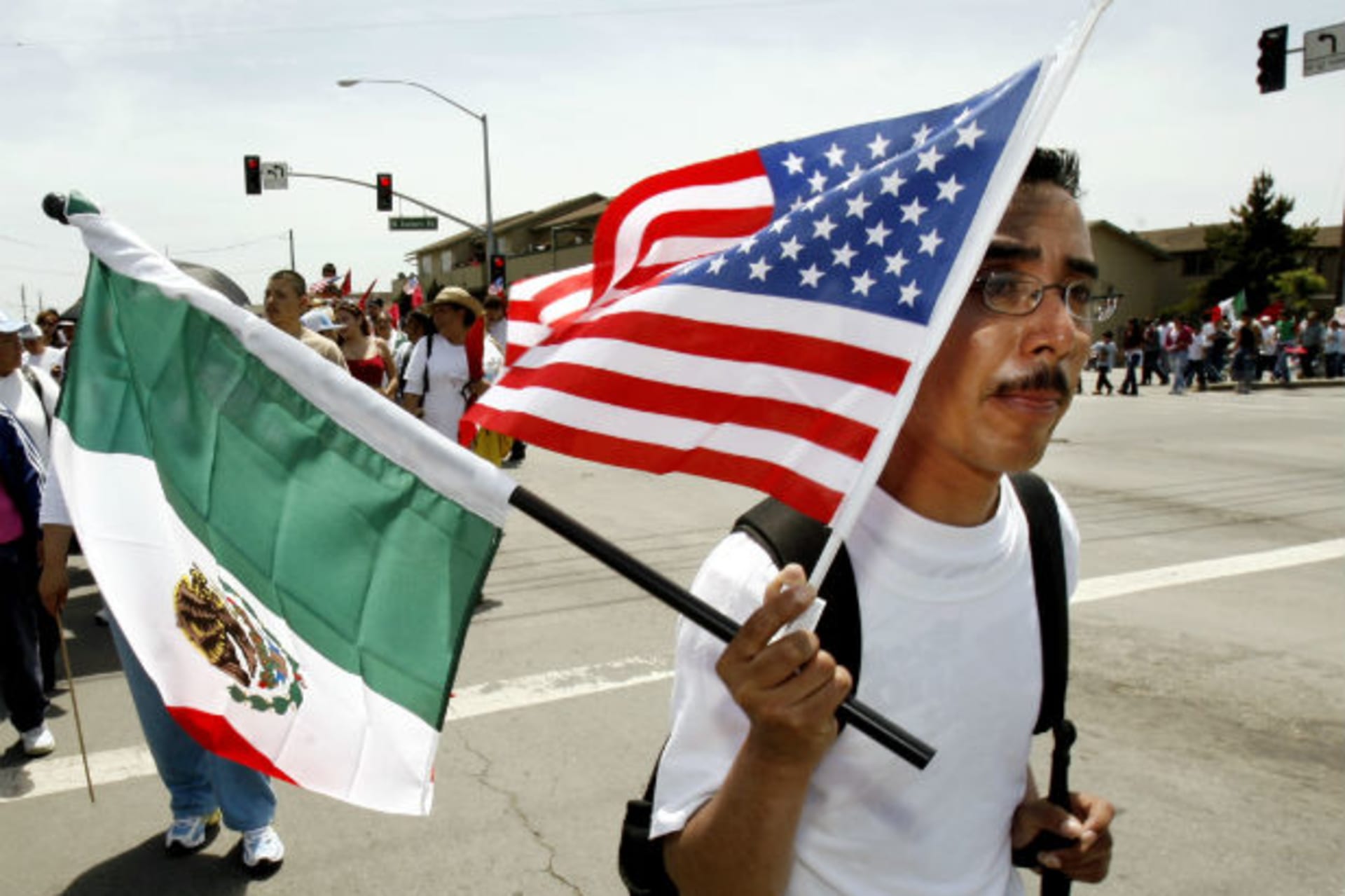 <p>A worker carries the flags of Mexico and the U.S. during a march through the streets of Salinas, California May 1, 2006 (Robert Galbraith/Courtesy Reuters).</p>
